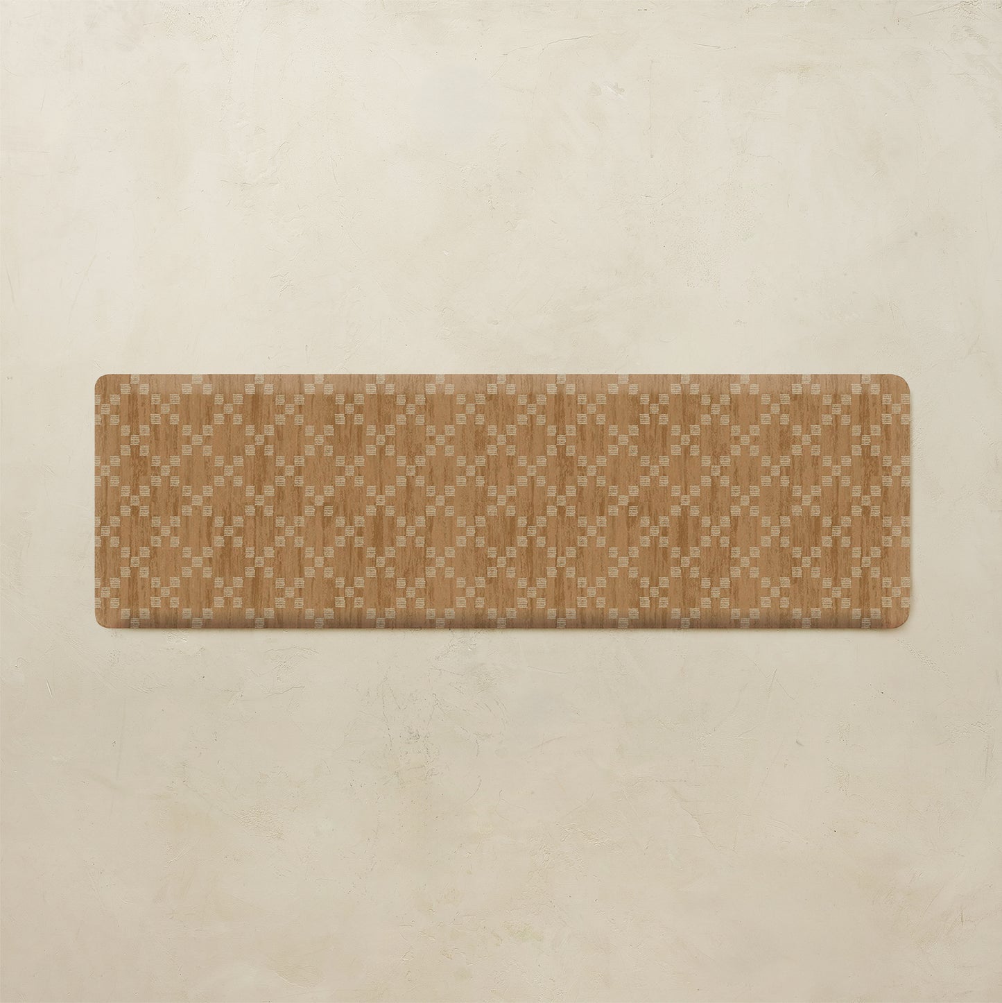 A rectangular floor mat with a tan and beige geometric diamond pattern, displayed on a textured beige background.