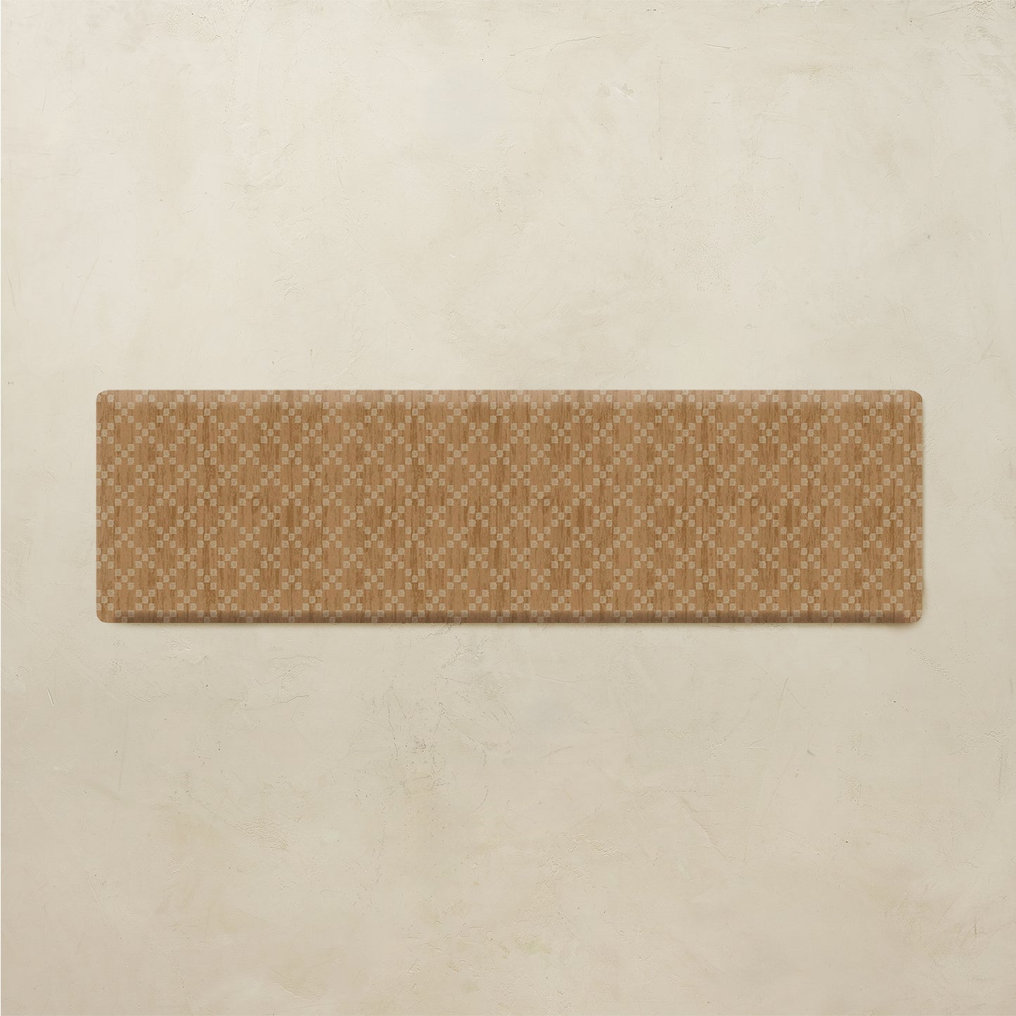 A rectangular tan rug with a repeating cream geometric lattice pattern, displayed against a textured beige plaster wall.