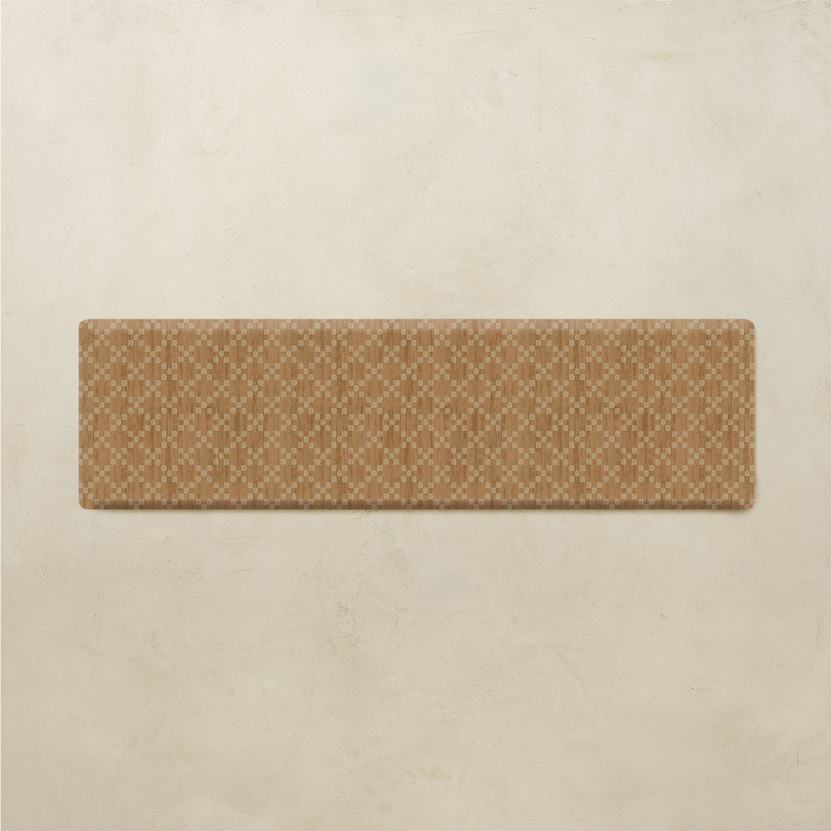 A rectangular tan rug with a repeating cream geometric lattice pattern, displayed against a textured beige plaster wall.