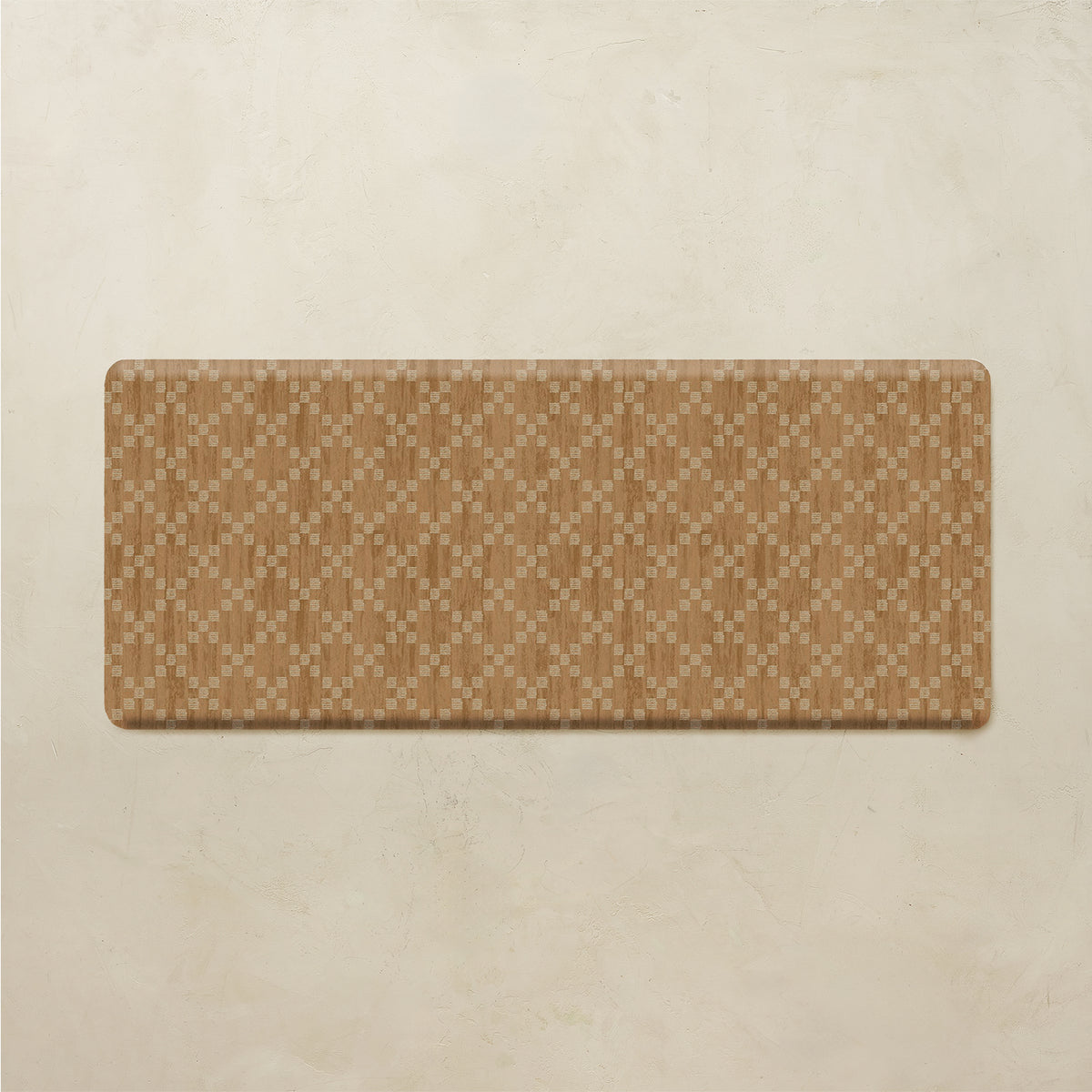 A rectangular mat with rounded corners featuring a tan and beige geometric diamond pattern, displayed on a textured beige background.