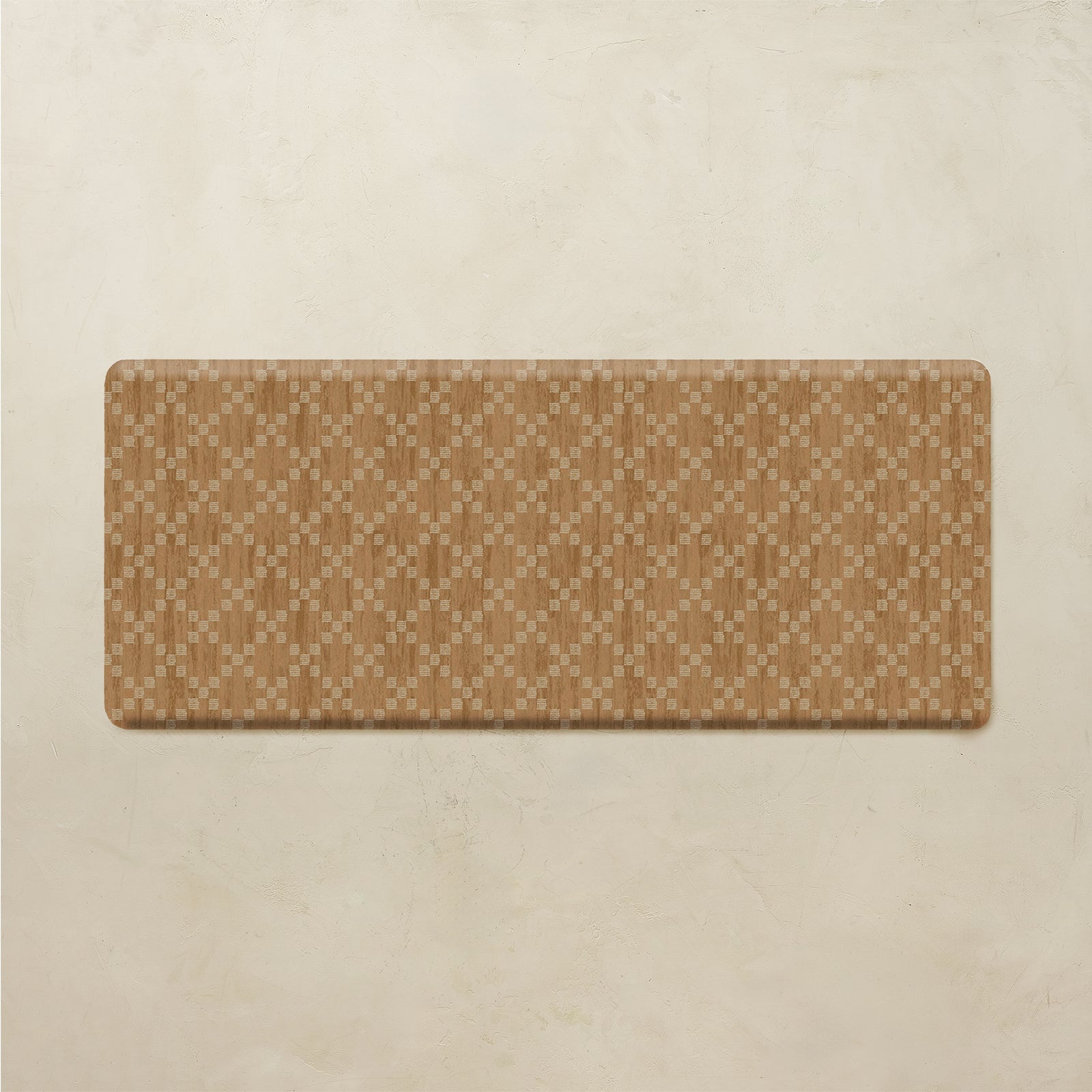 A rectangular mat with rounded corners featuring a tan and beige geometric diamond pattern, displayed on a textured beige background.