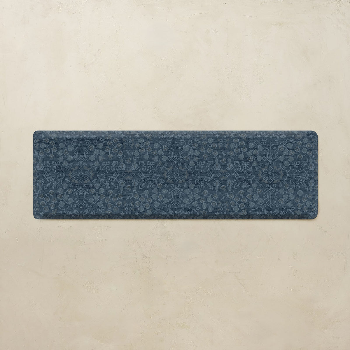 A rectangular navy blue runner rug with an intricate floral and botanical pattern, displayed flat against a textured beige background.