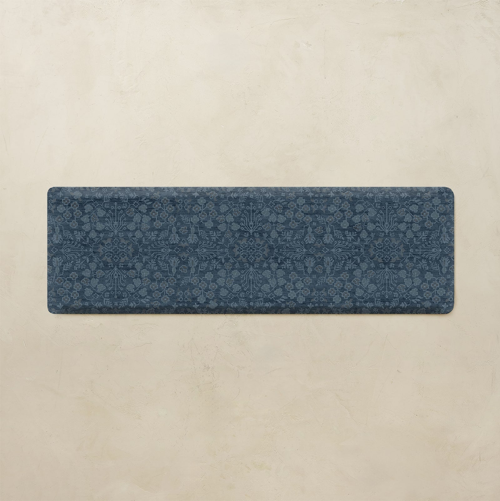 A rectangular navy blue runner rug with an intricate floral and botanical pattern, displayed flat against a textured beige background.