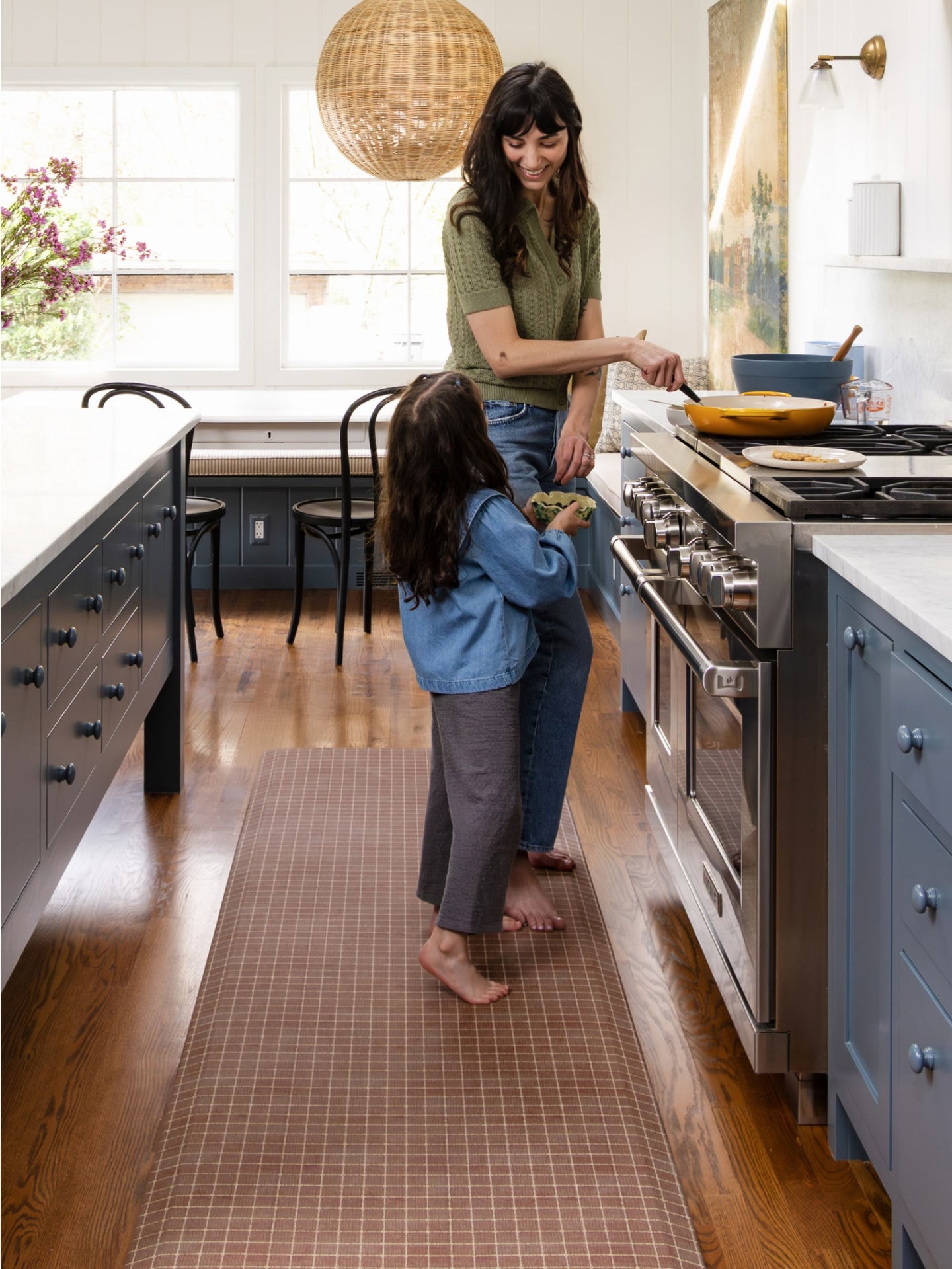 Woman and child in a modern kitchen with wooden floor and large windows.