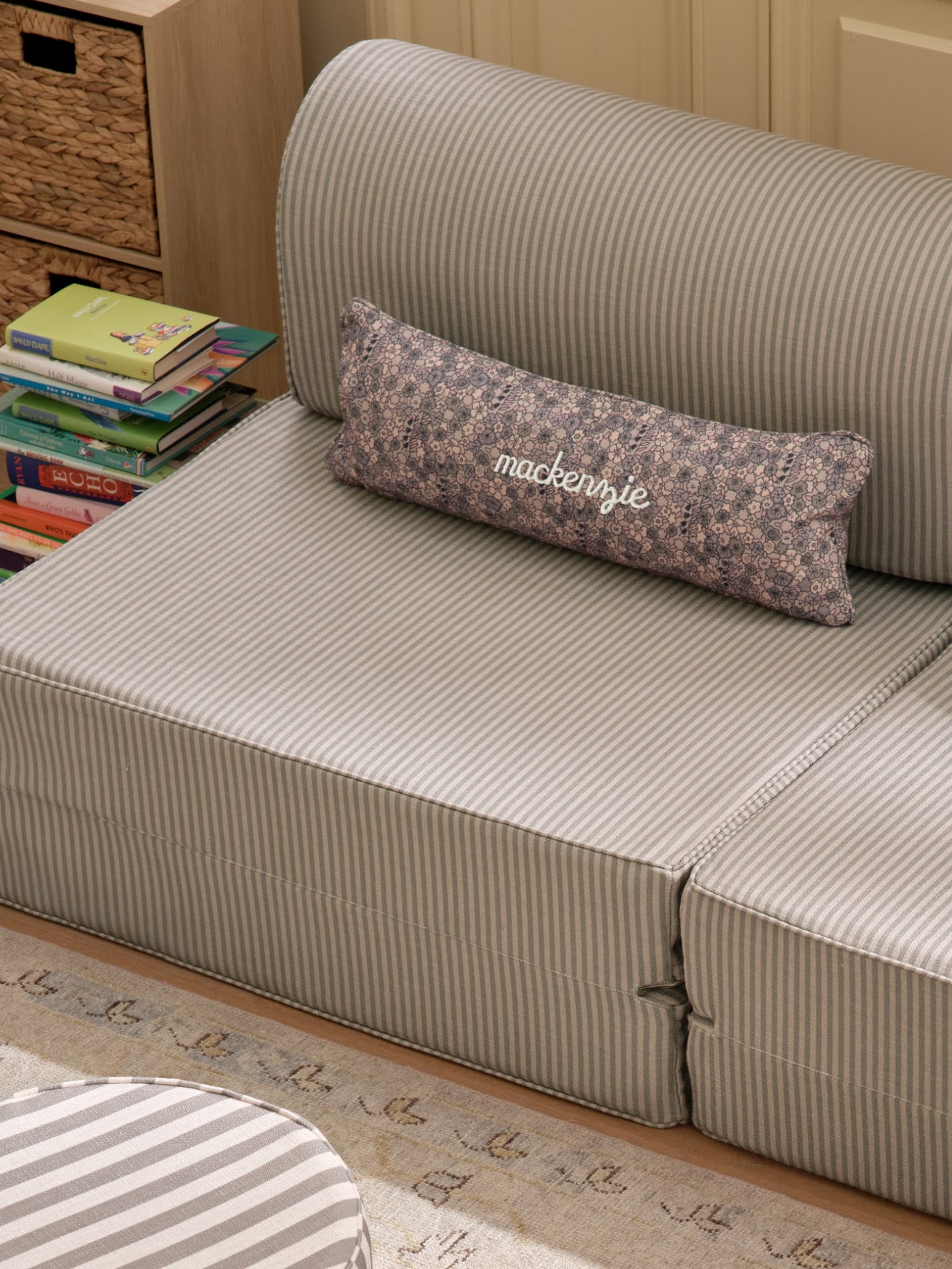 Green striped play couch with floral-patterned lumbar pillow with name "mackenzie" embroidered on it