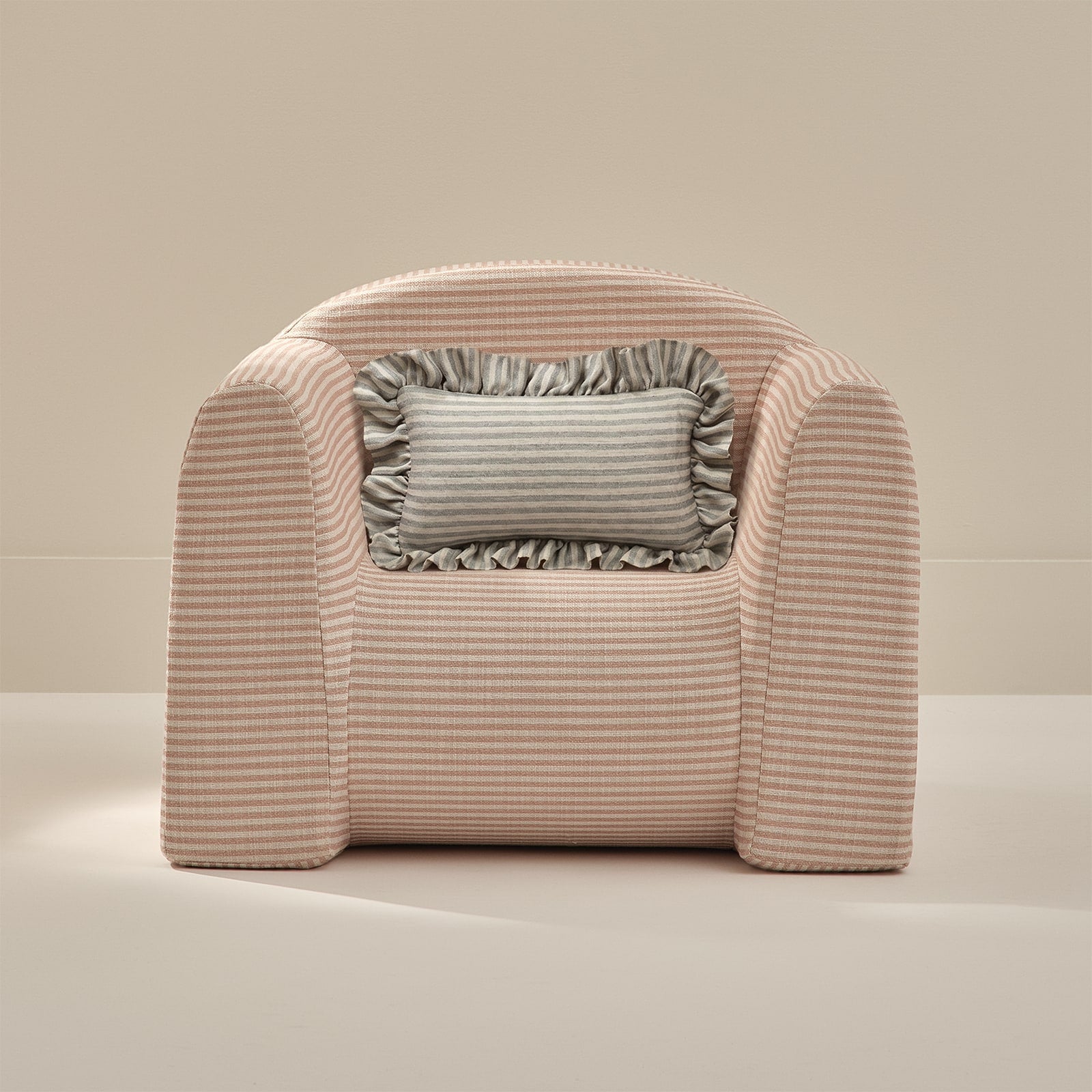 Pink armchair with a striped pattern and a gray pillow on a beige background