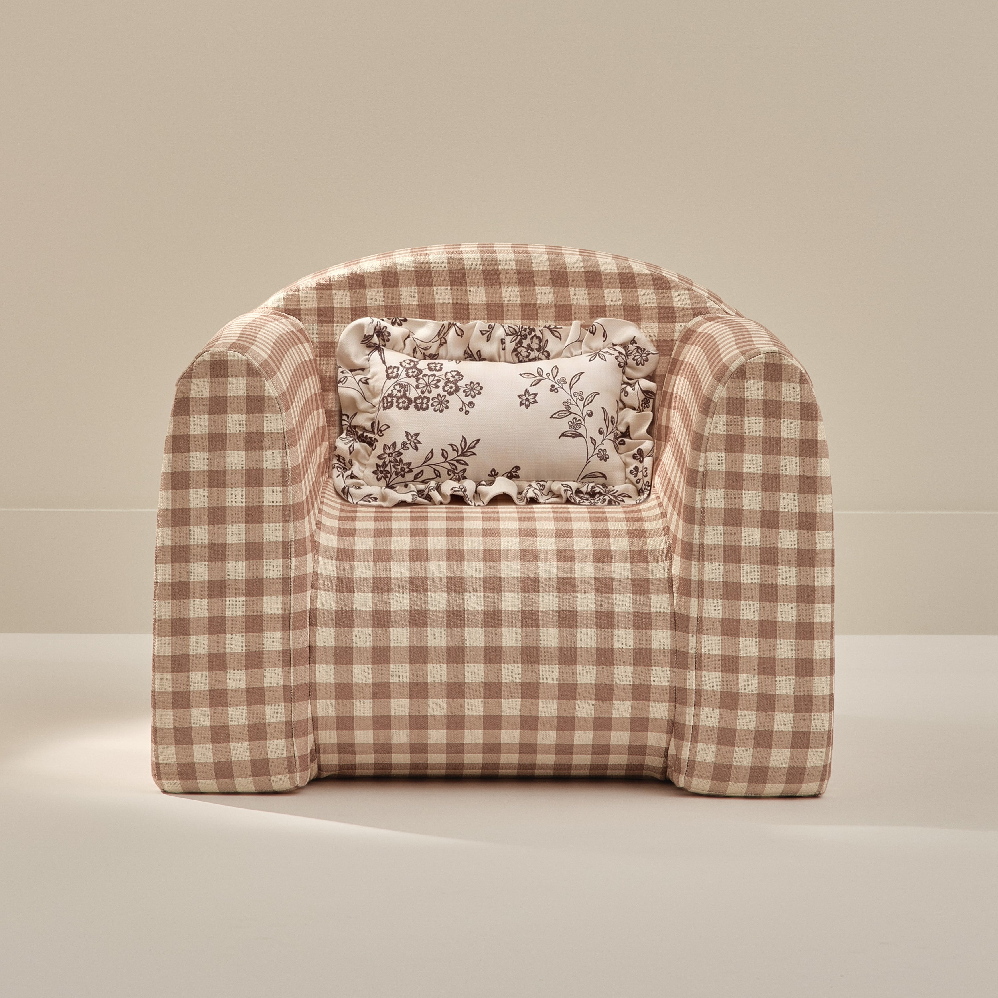 Checkered armchair with a decorative pillow on a beige background