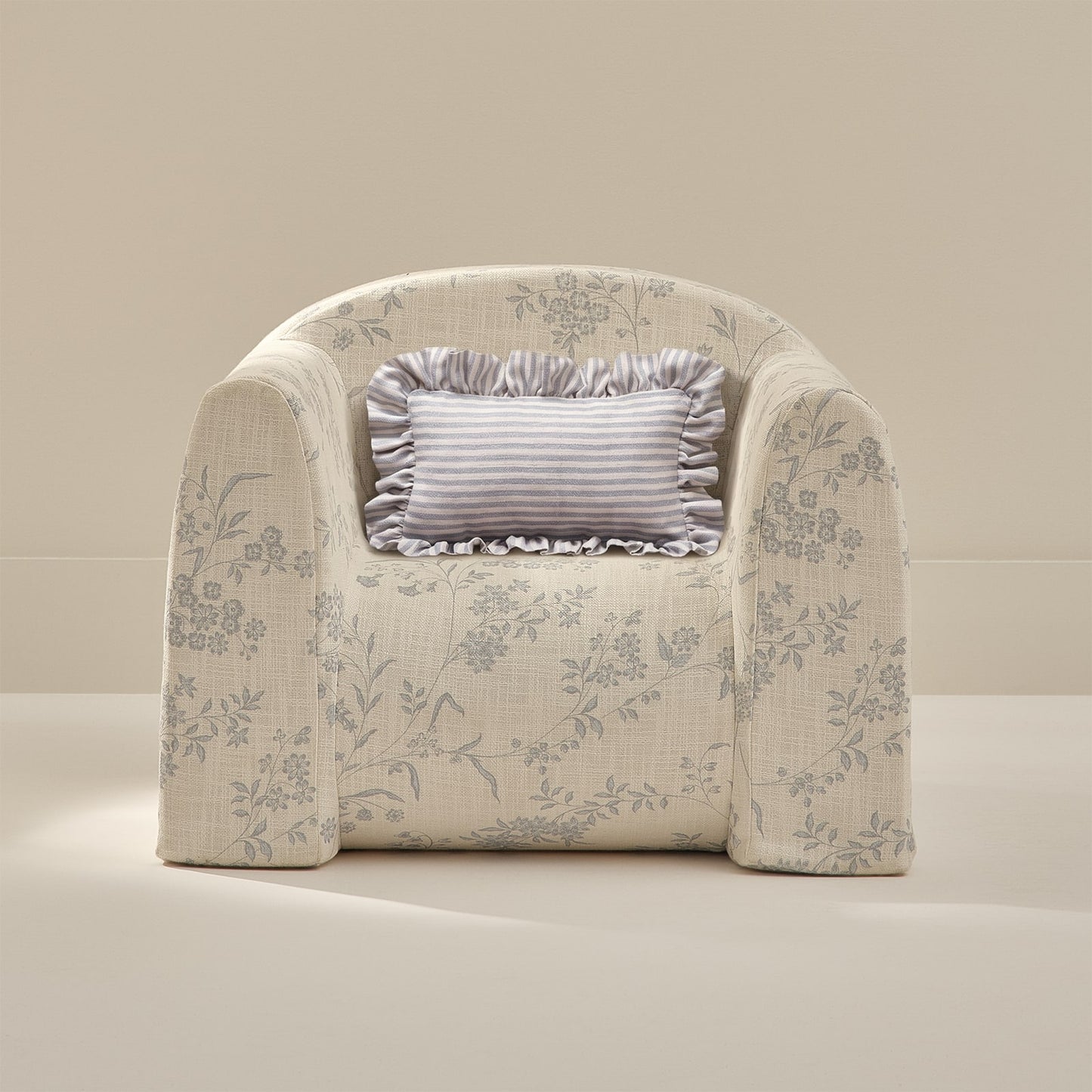 Floral-patterned armchair with a decorative pillow on a beige background