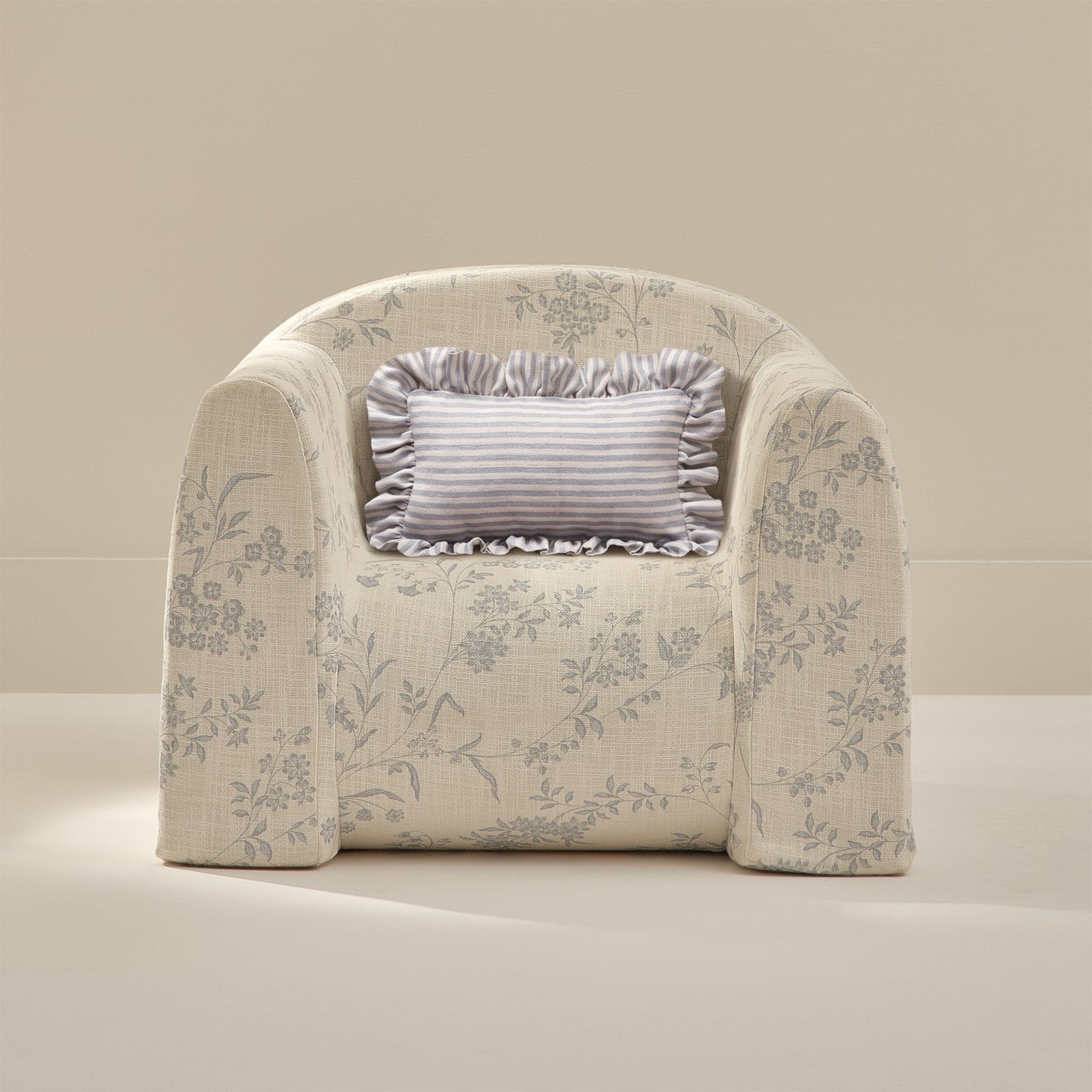 Floral-patterned armchair with a decorative pillow on a beige background