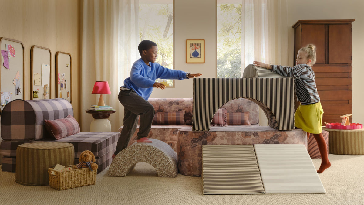 2 young kids playing in a living room with neutral color foam block shapes