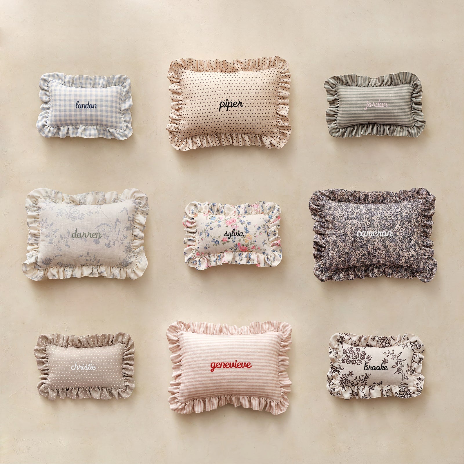 Set of decorative pillows with names embroidered on them against a beige background