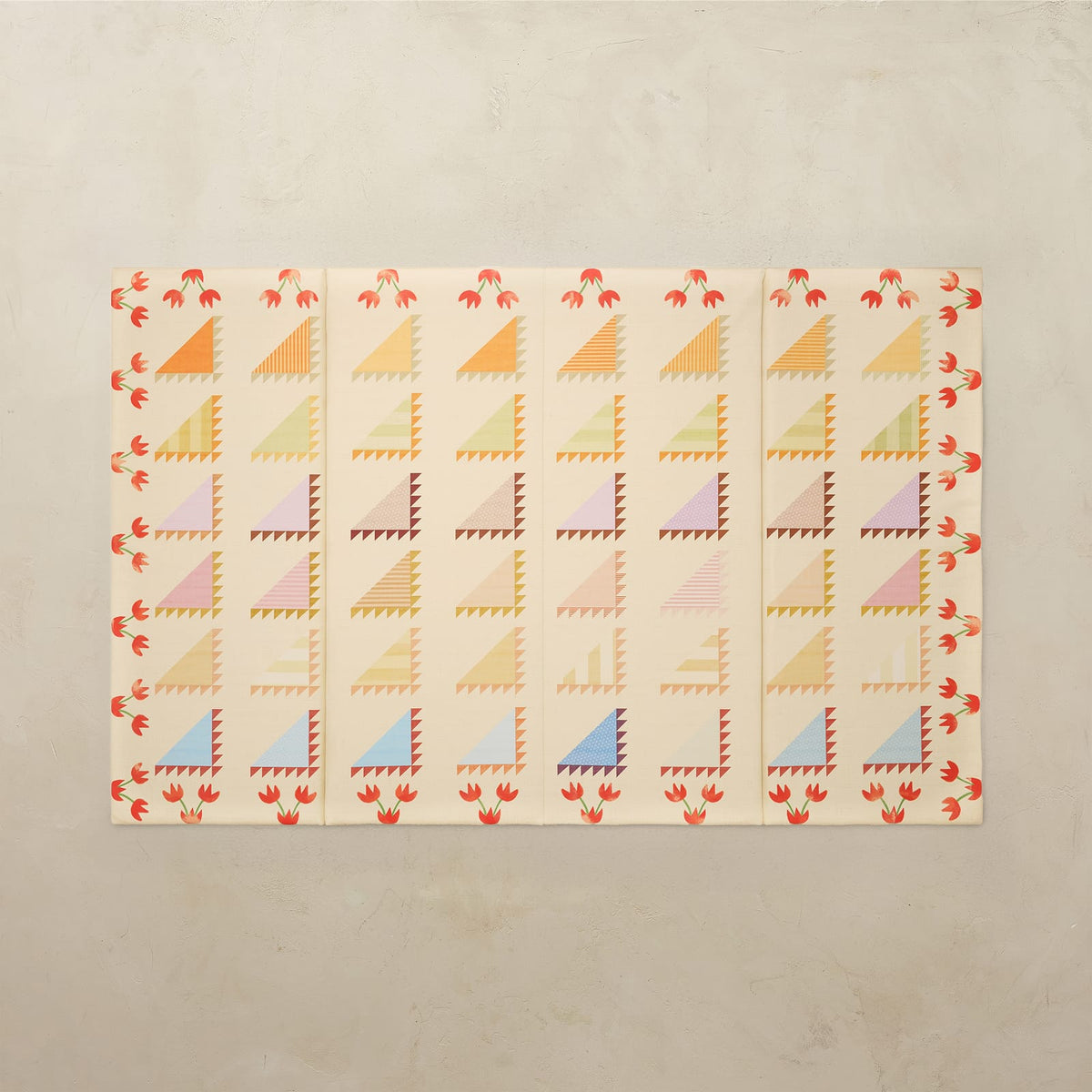 Sylvia Kaleidoscope 4x6 tumbling mat with quilt-inspired orange, pink, green and blue triangles and a red tulip border on a cream base