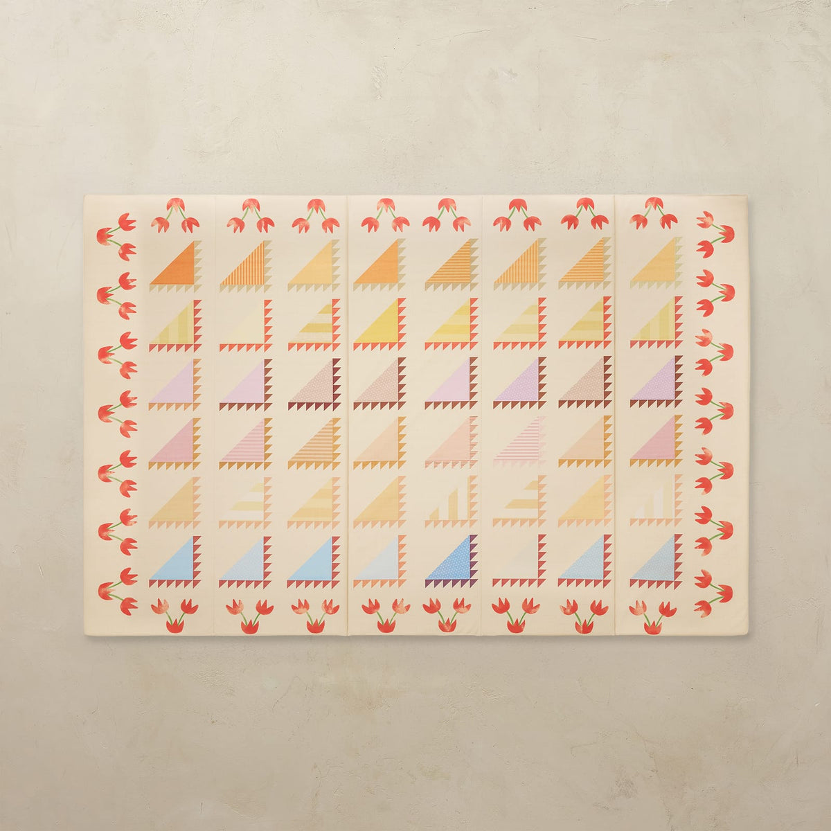 Sylvia Kaleidoscope 5x7.5 tumbling mat with quilt-inspired orange, pink, green and blue triangles and a red tulip border on a cream base