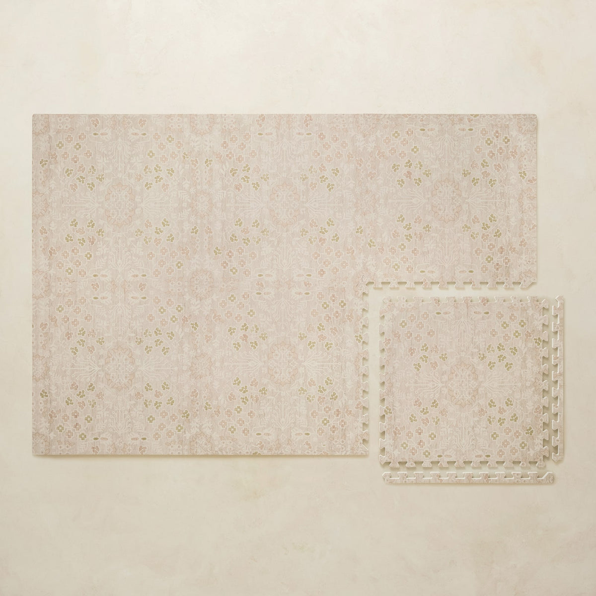A 4x6 blush floral foam play mat shown beside a single interlocking tile to compare sizes, photographed from above on a beige background.