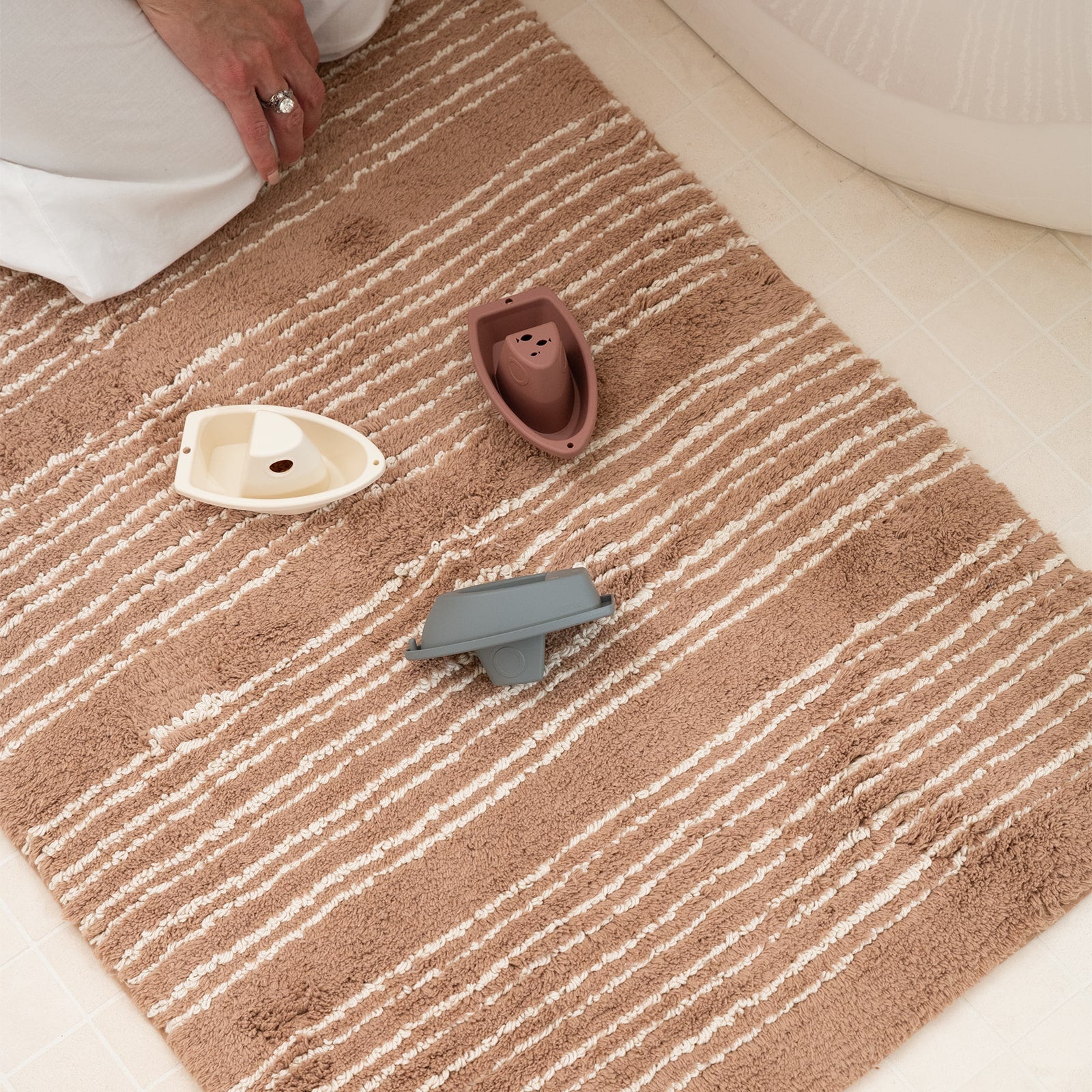 Small decorative items on a brown and beige striped bath rug.