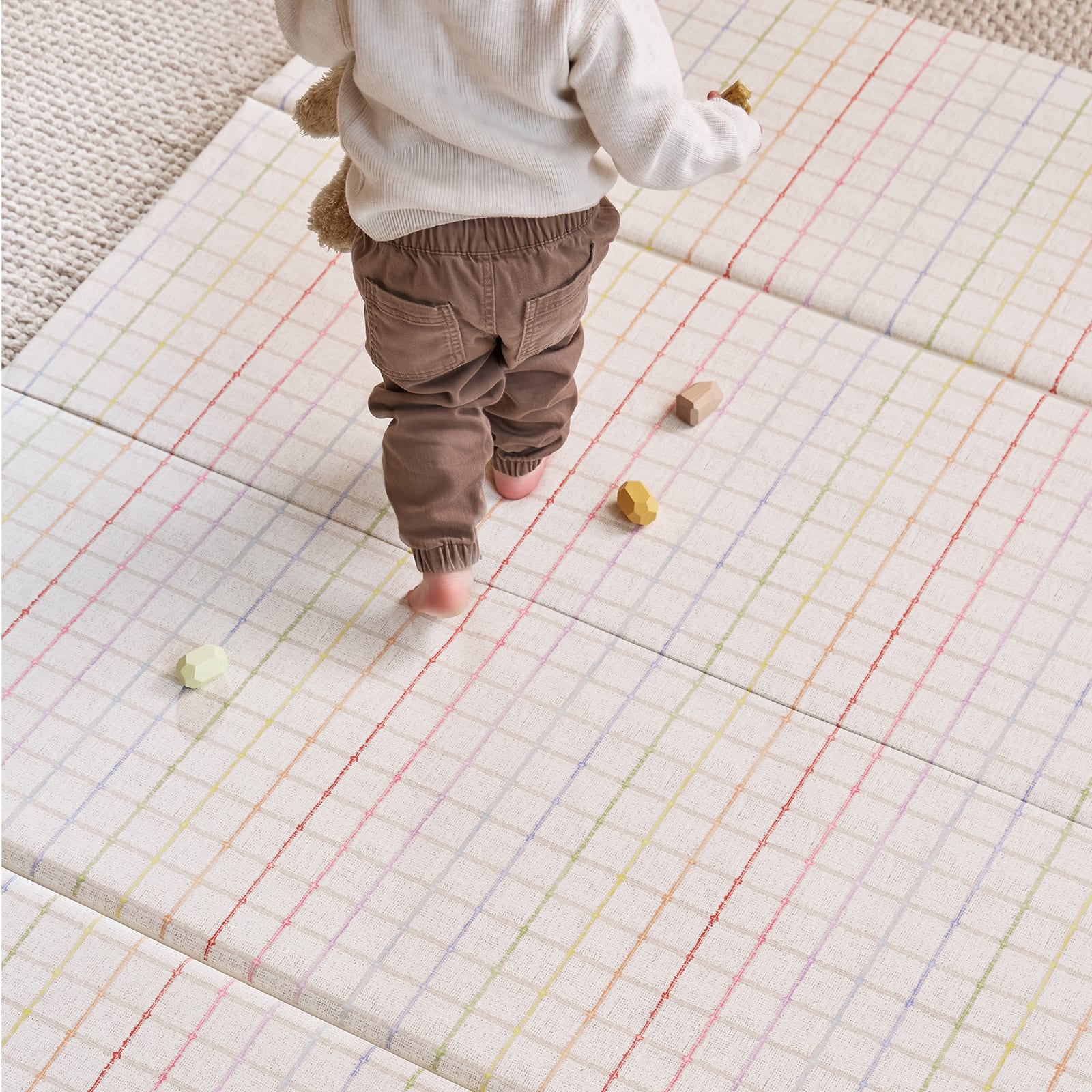 Child walking on a colorful grid-patterned mat