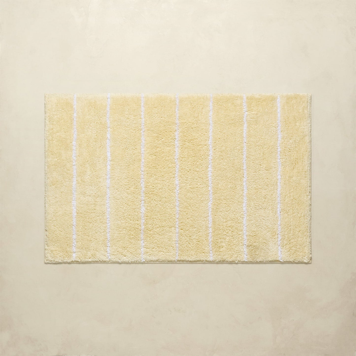 Yellow bath mat with white stripes on a beige background