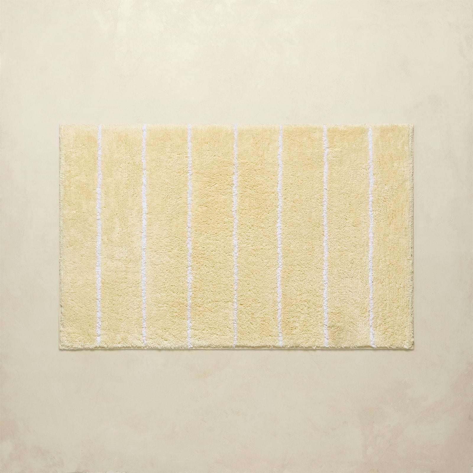 Yellow bath mat with white stripes on a beige background