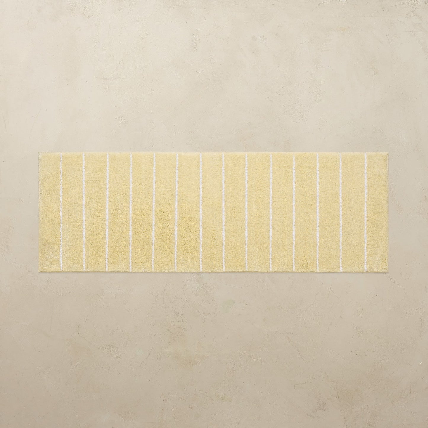 Rectangular bath mat with yellow stripes on a beige background