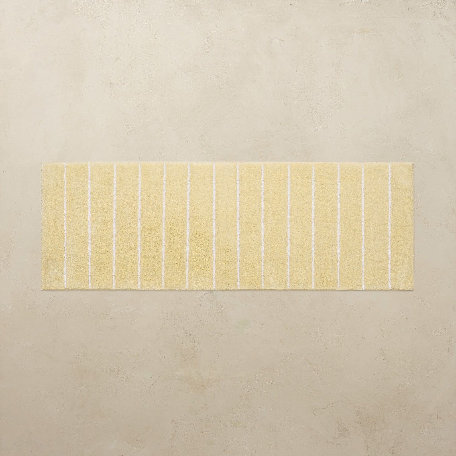 Rectangular bath mat with yellow stripes on a beige background