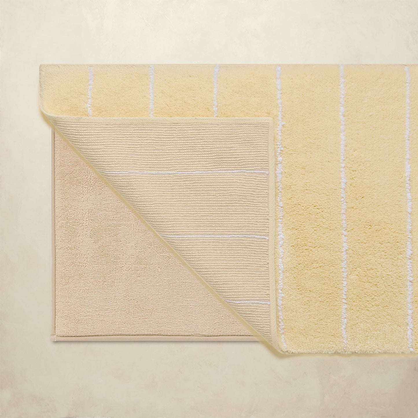 Yellow bath rug with striped pattern on a beige background