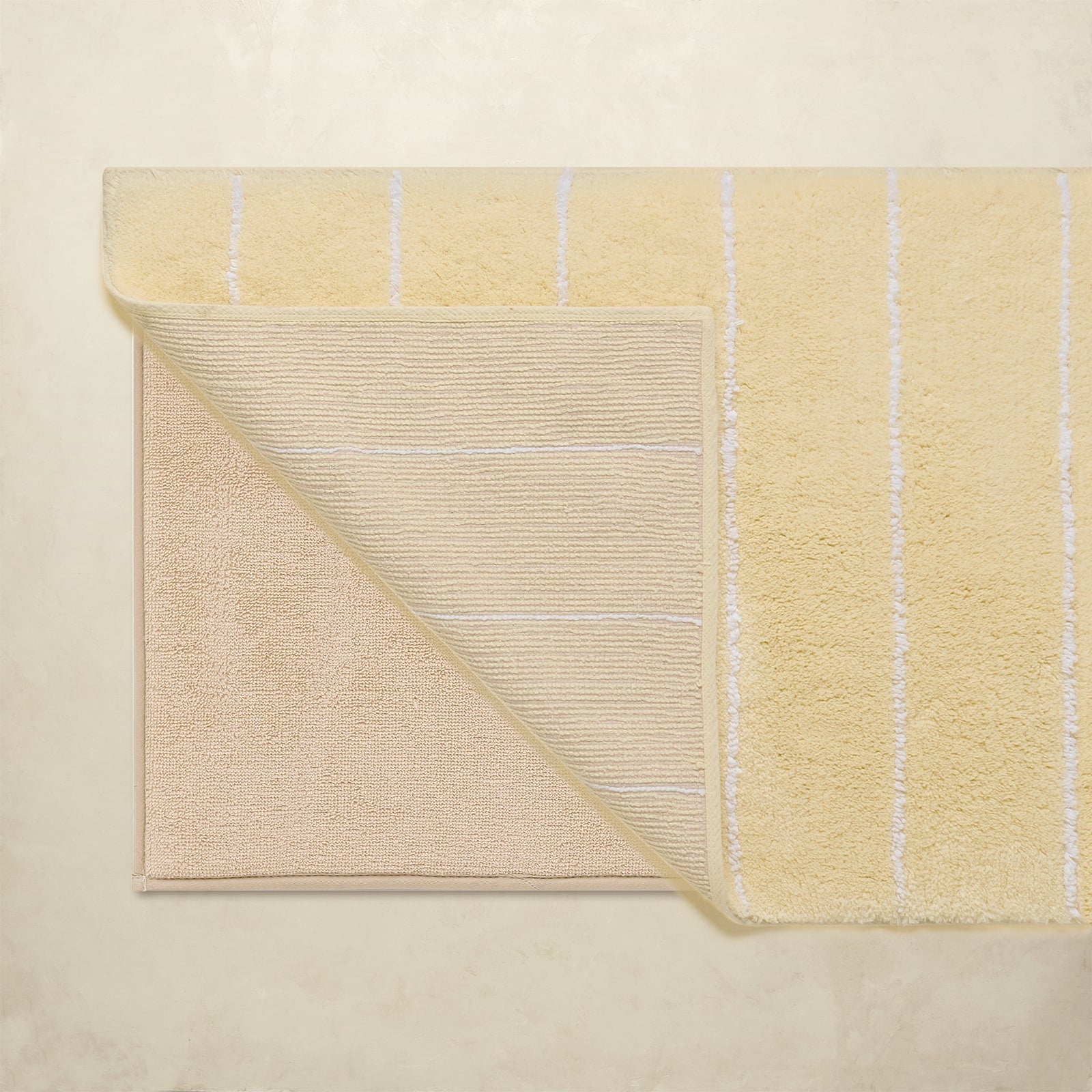 Yellow bath rug with striped pattern on a beige background