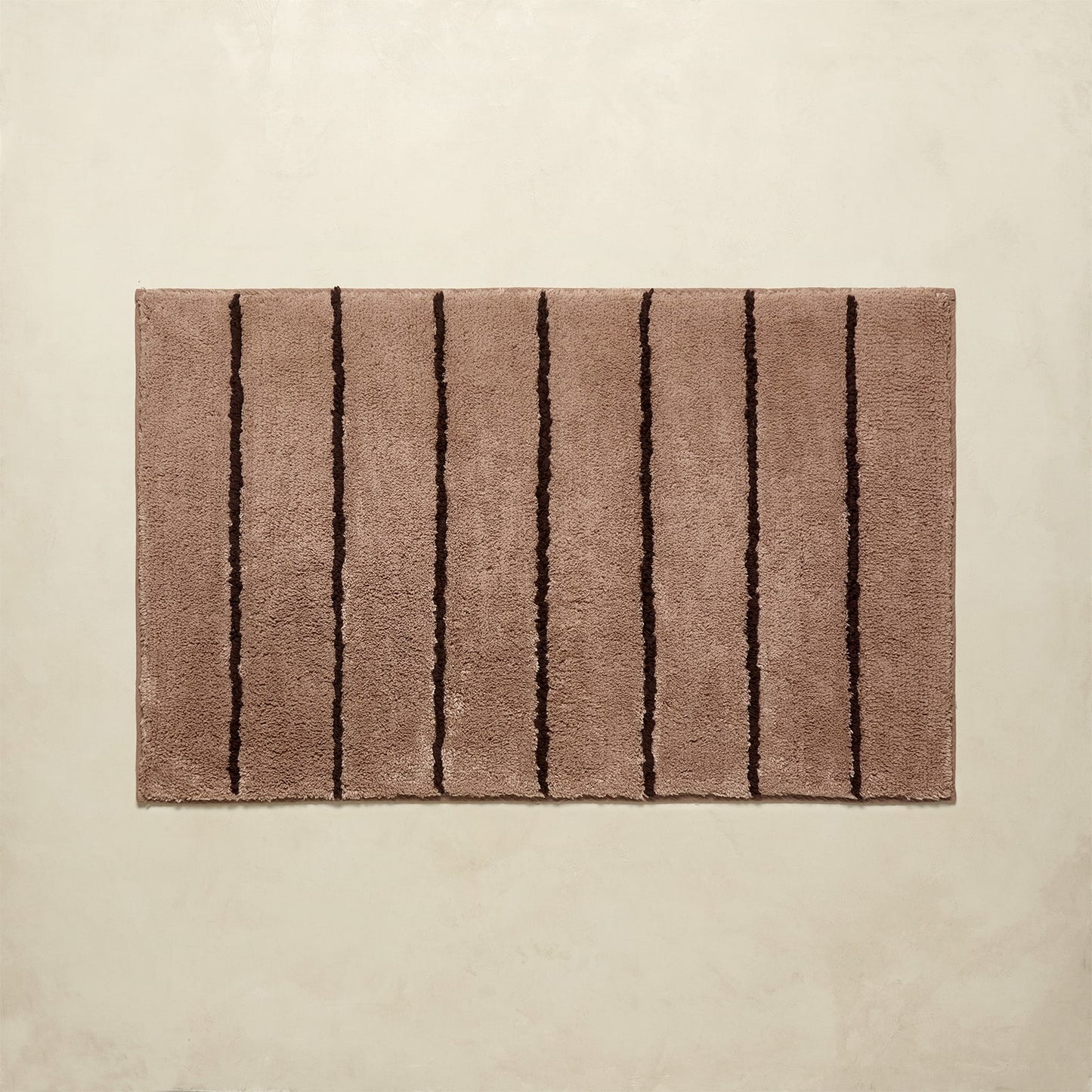 Brown bath rug with black stripes on a beige background