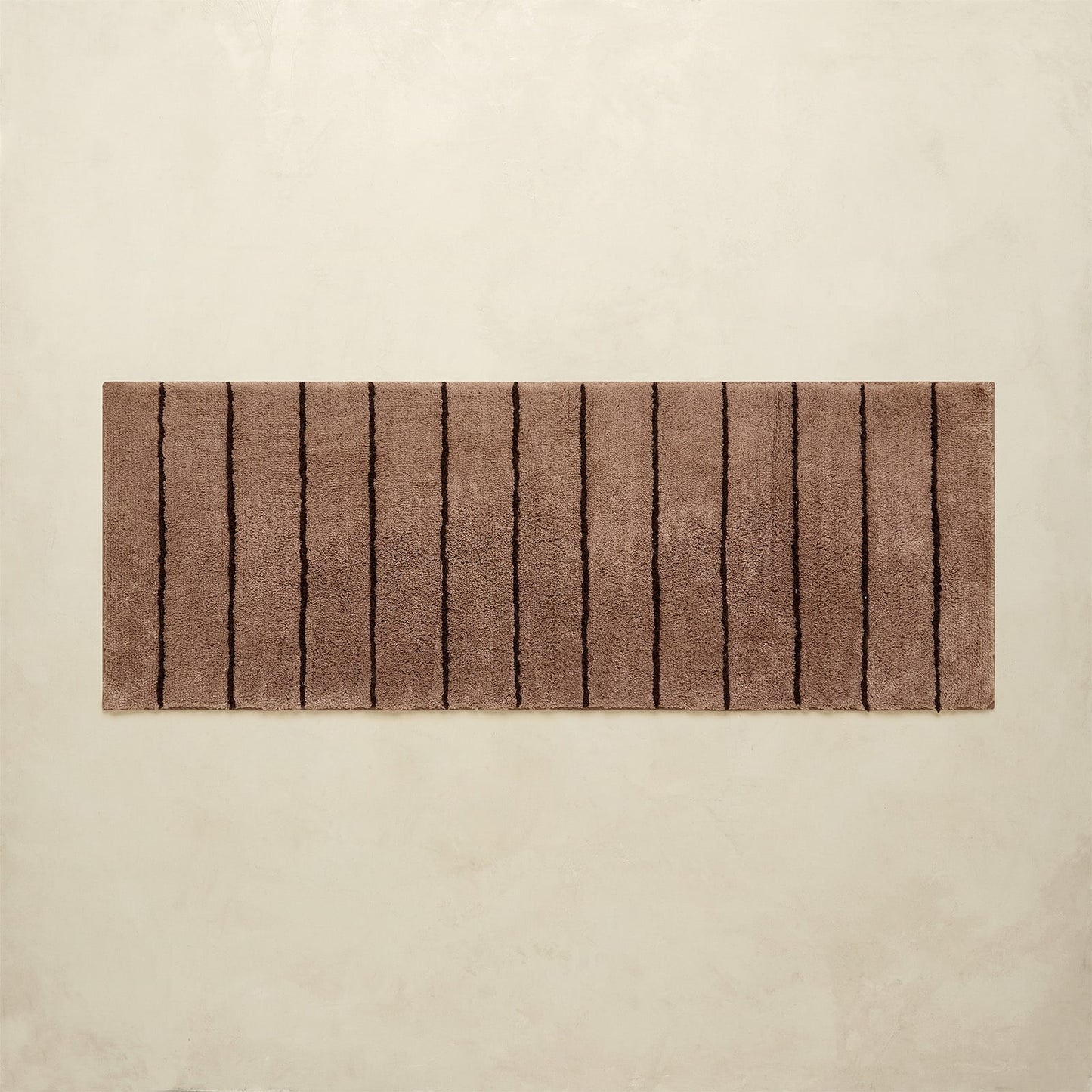 Rectangular brown bath rug with striped pattern on a beige background