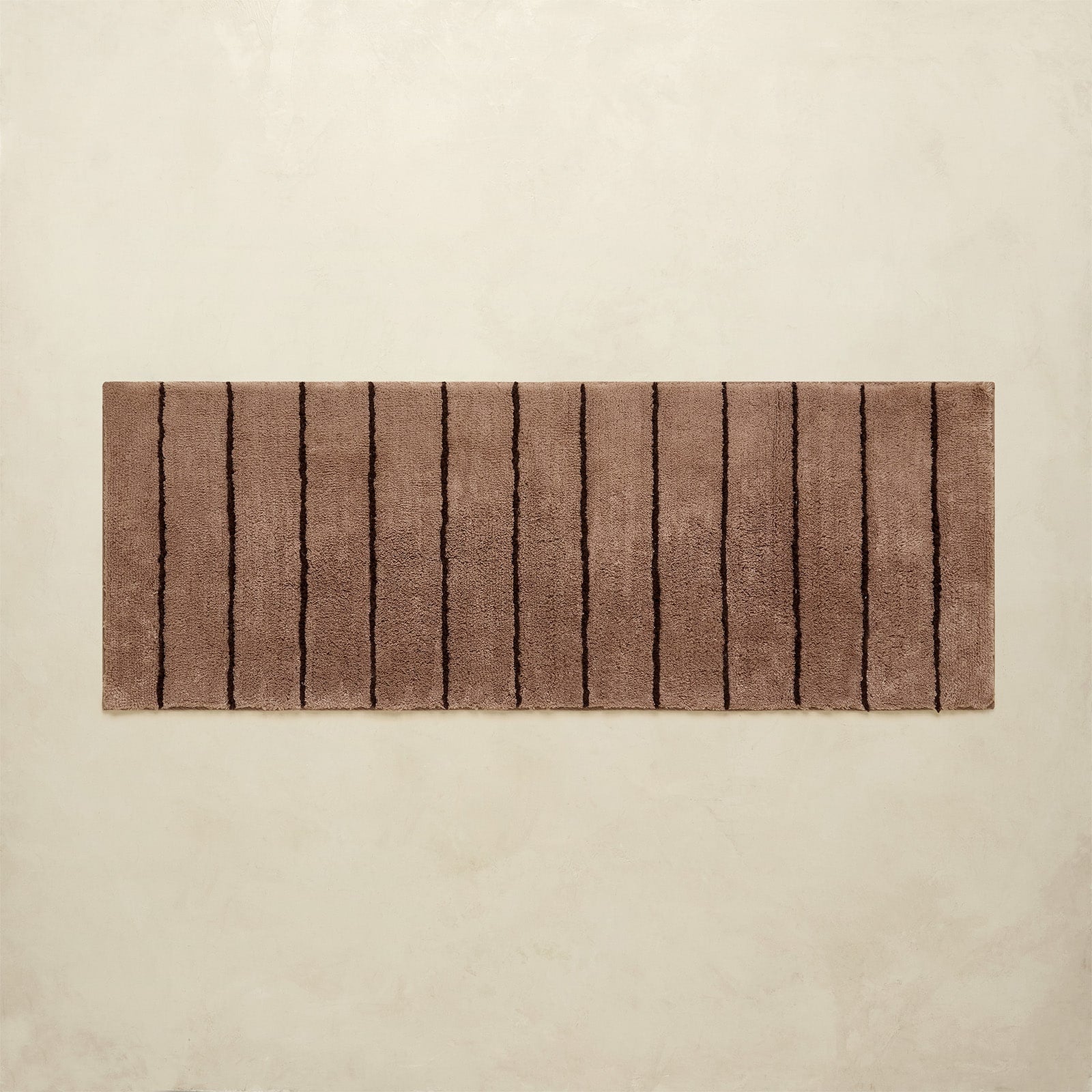 Rectangular brown bath rug with striped pattern on a beige background