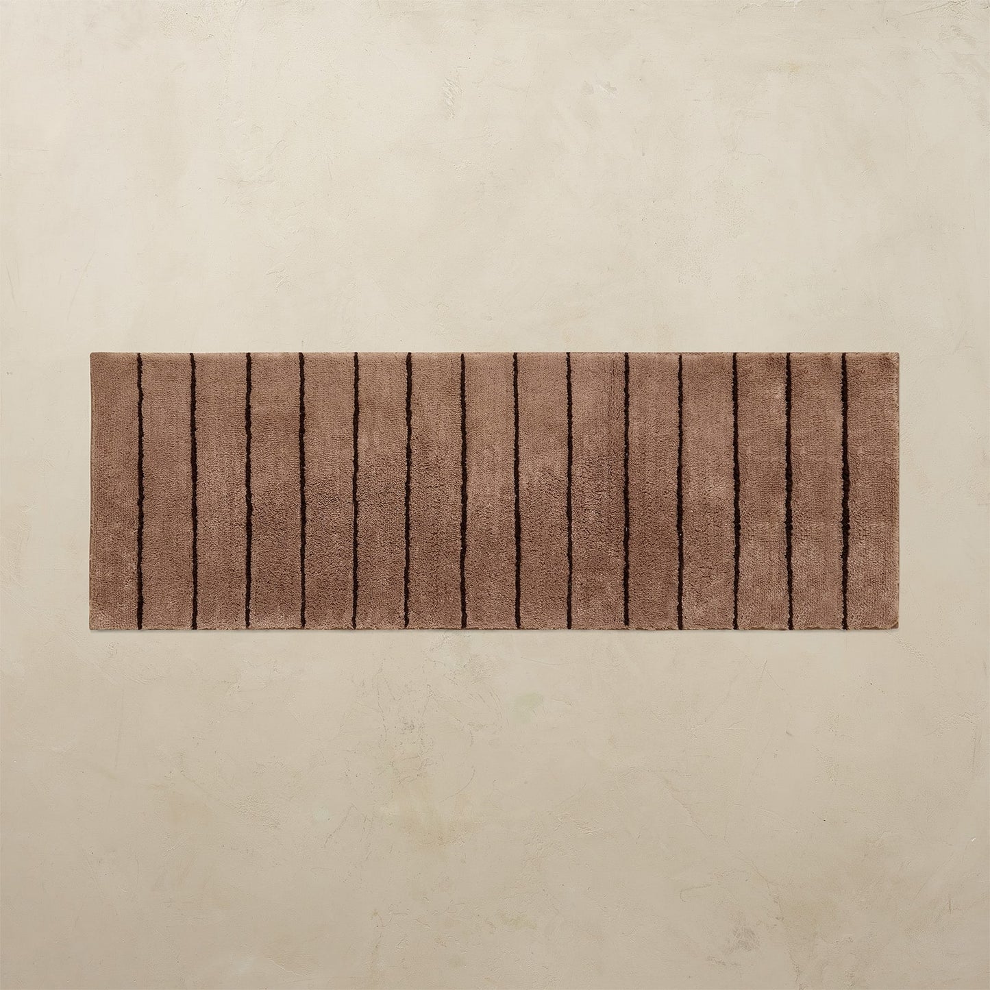 Brown bath mat with a striped pattern on a beige background