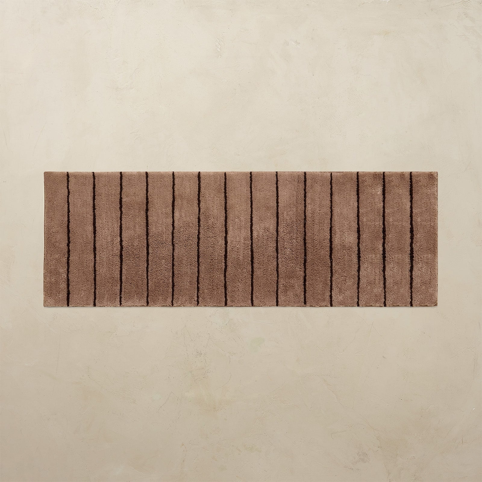 Brown bath mat with a striped pattern on a beige background