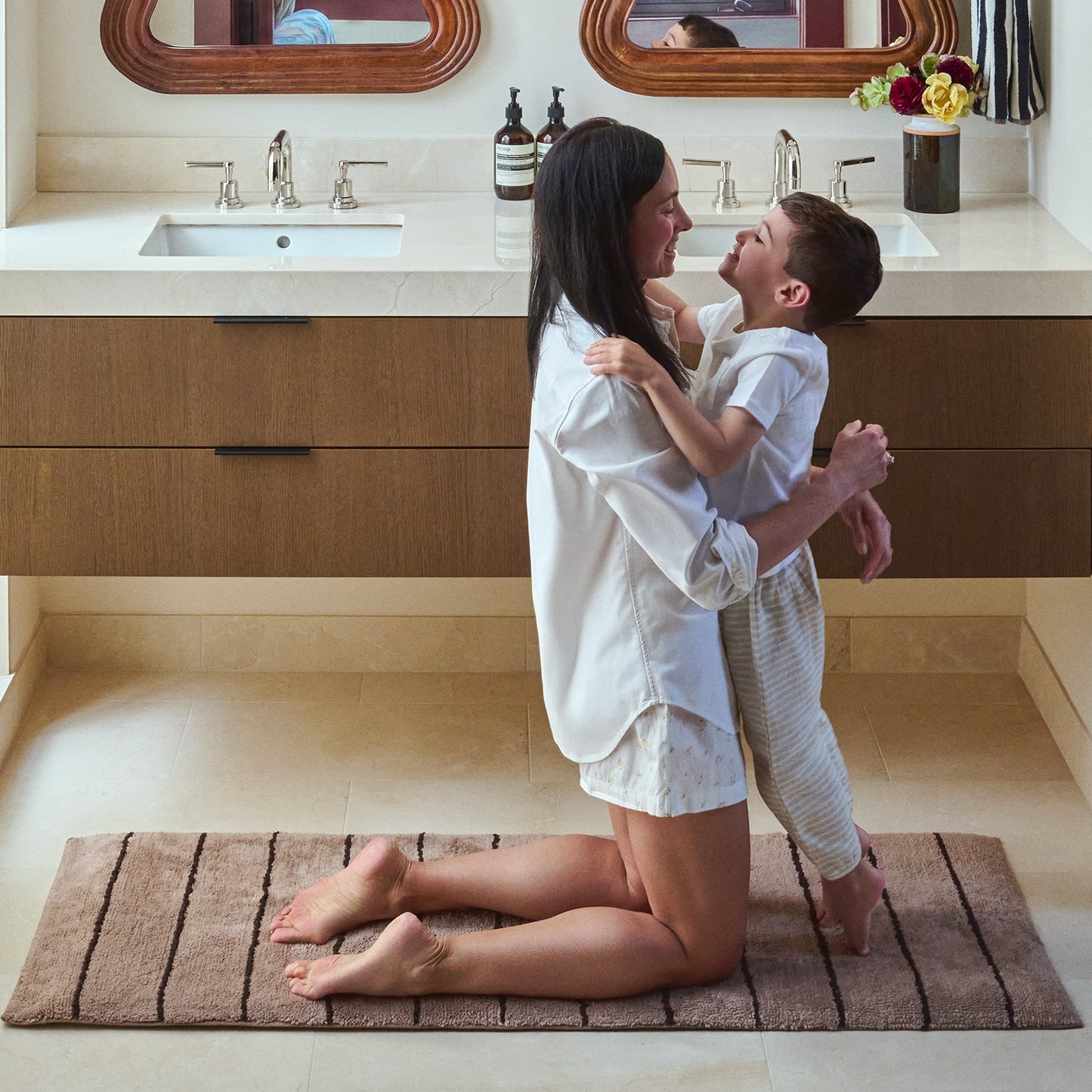Woman and child embracing on a bath mat in a bathroom