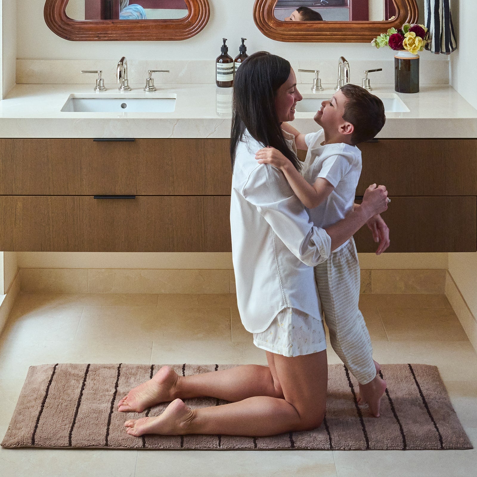 Woman and child embracing on a bath mat in a bathroom