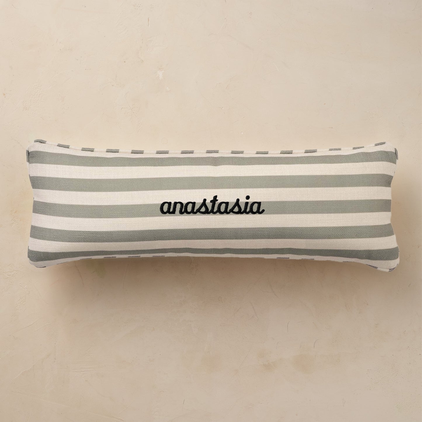 Striped pillow with 'anastasia' embroidery on a beige background