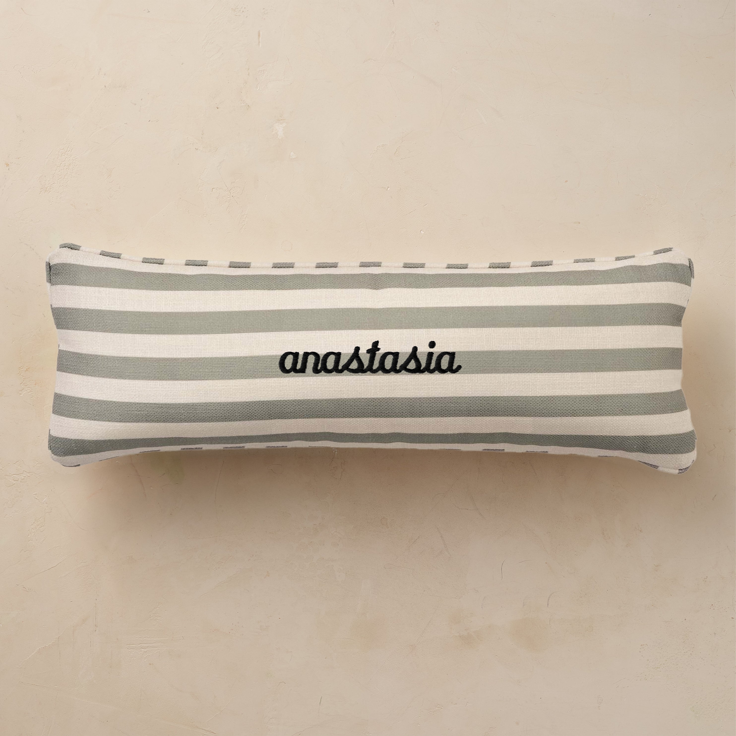 Striped pillow with 'anastasia' embroidery on a beige background