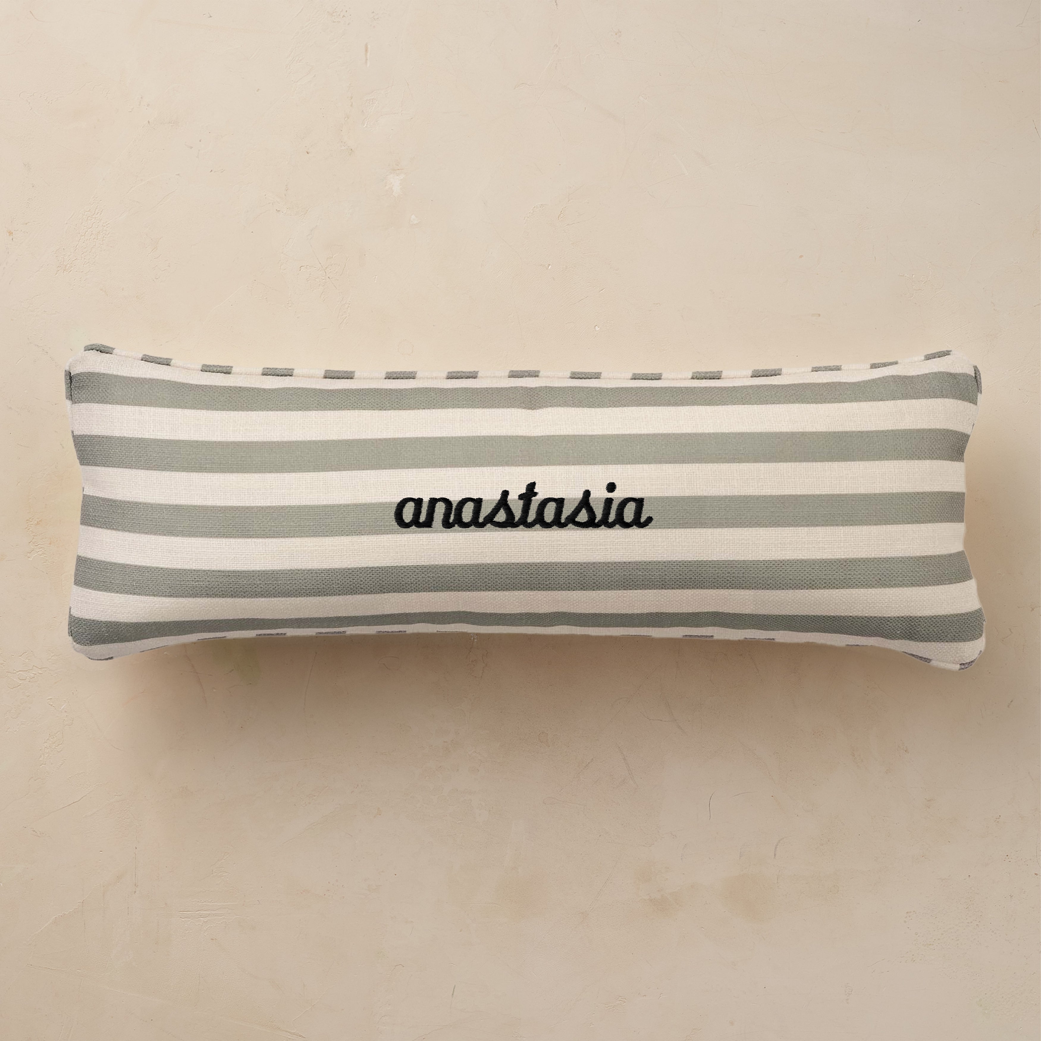 Striped pillow with 'anastasia' embroidery on a beige background