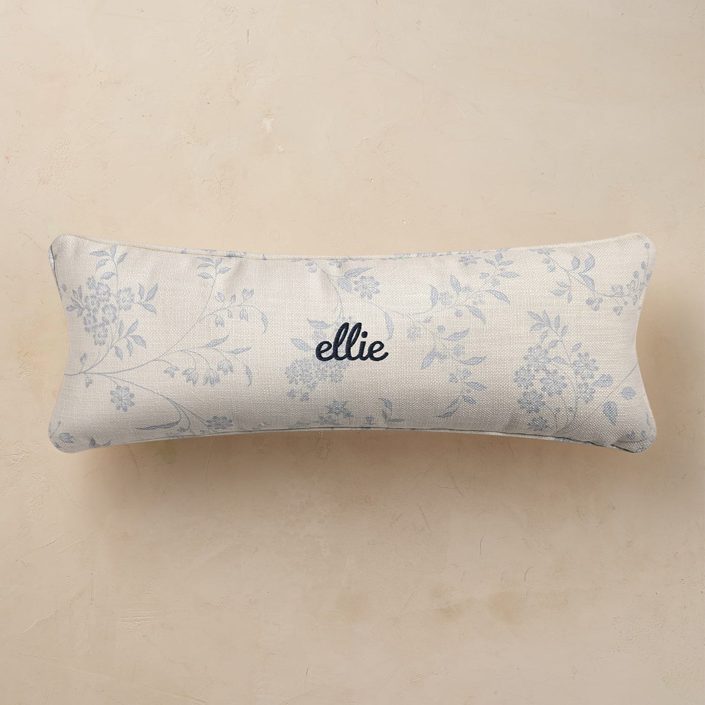 Floral-patterned pillow with 'ellie' branding on a beige background