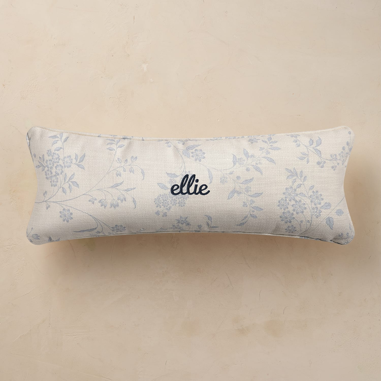 Floral-patterned pillow with 'ellie' branding on a beige background