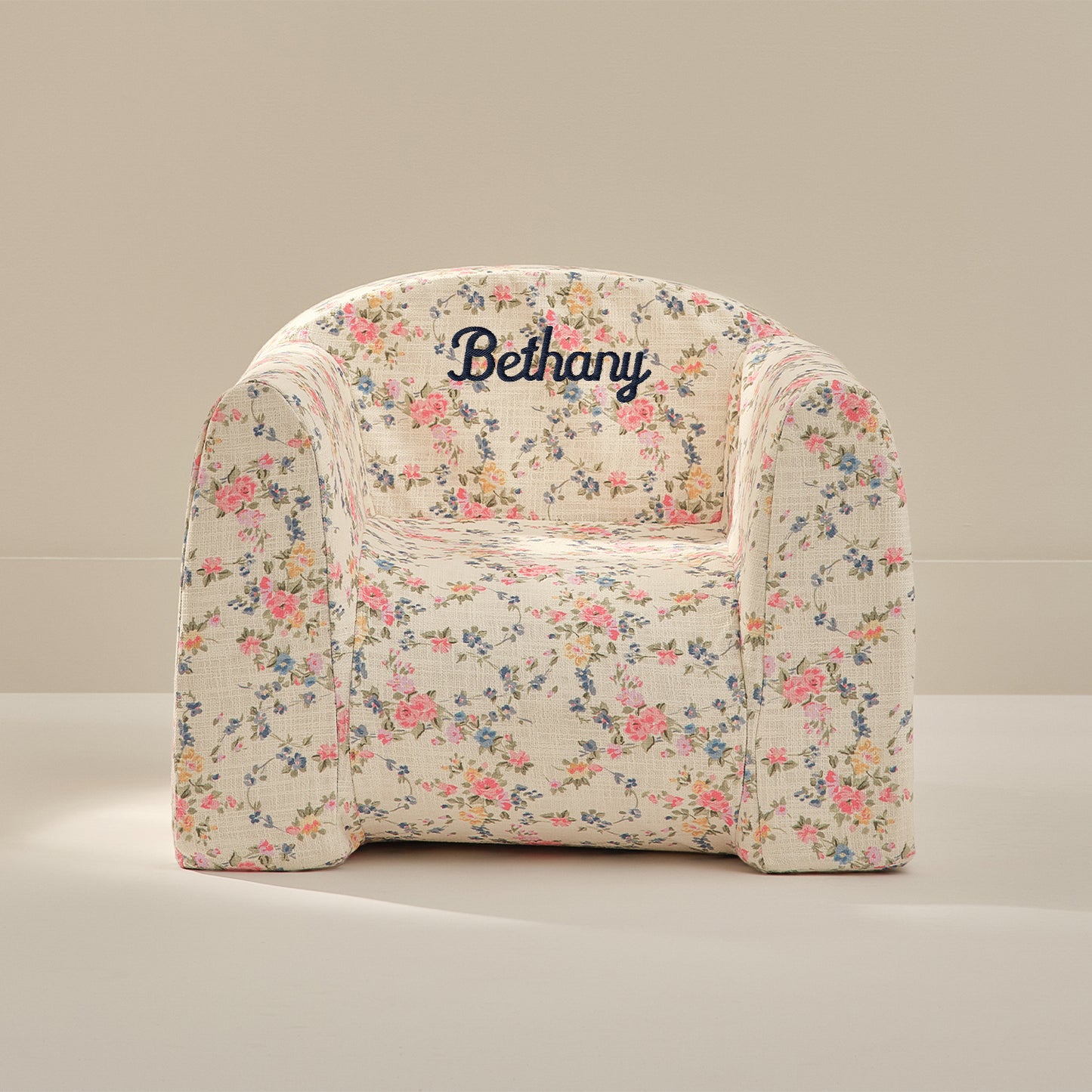 Floral-patterned chair with 'Bethany' embroidered on it against a beige background