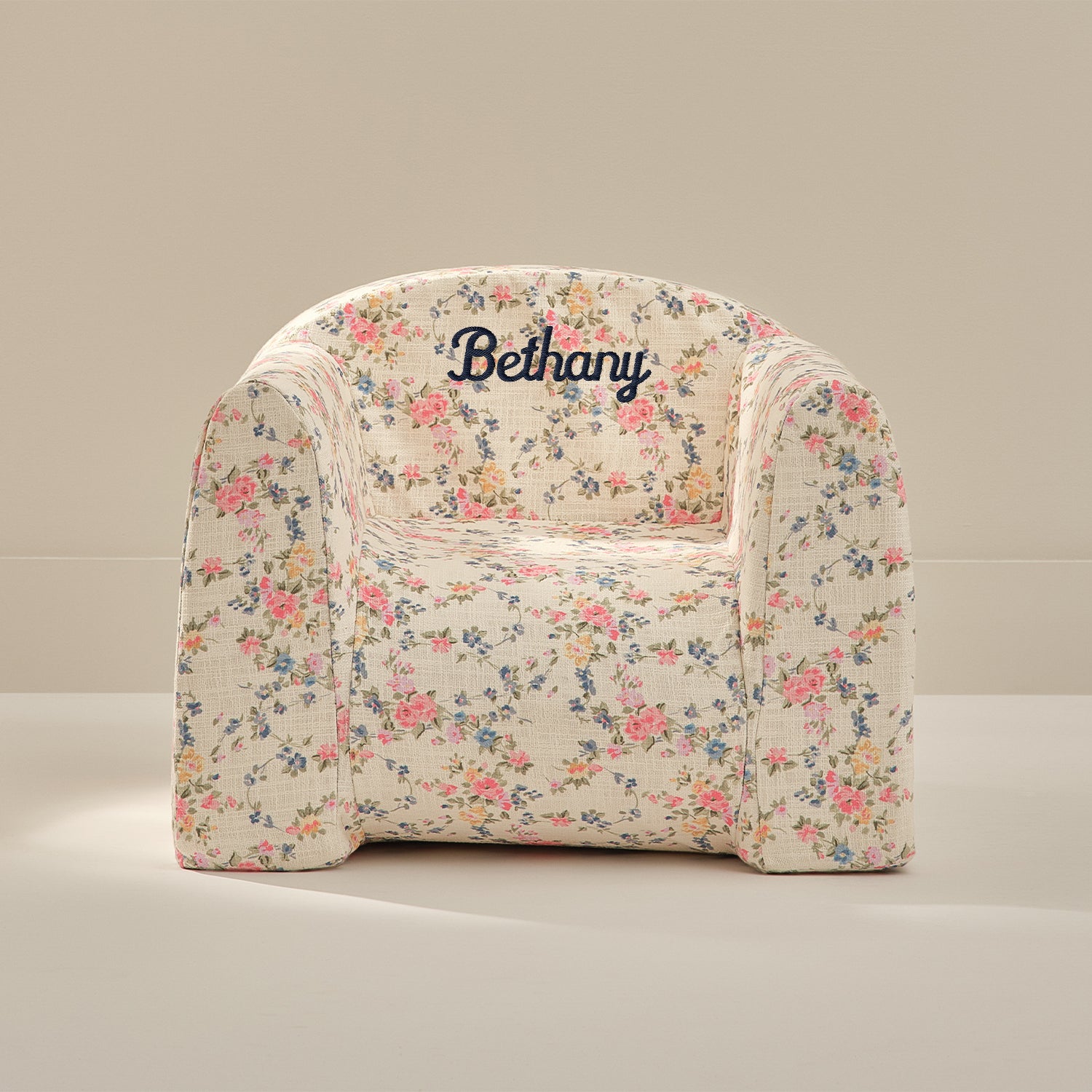 Floral-patterned chair with 'Bethany' embroidered on it against a beige background