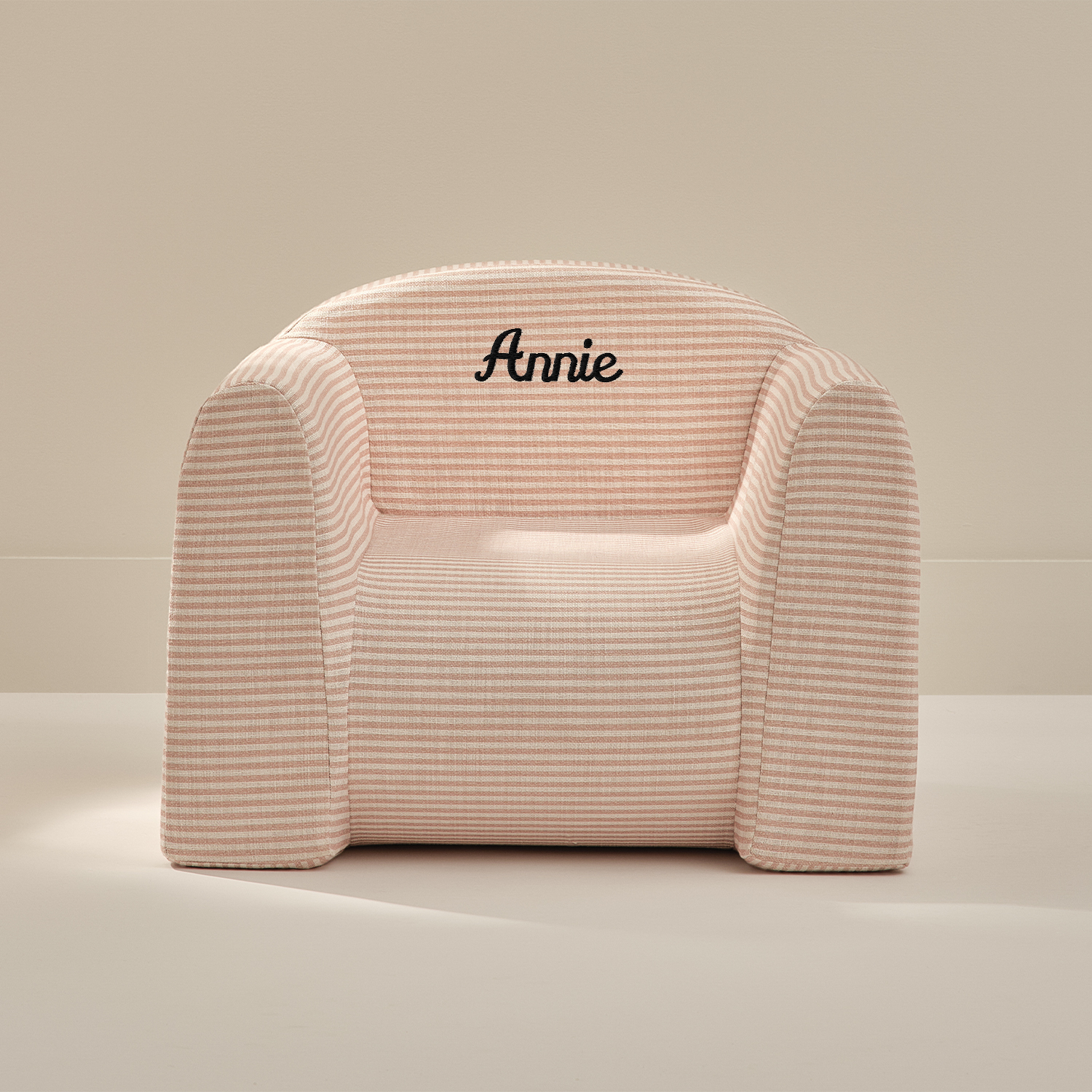 Pink armchair with 'Annie' embroidery on a beige background