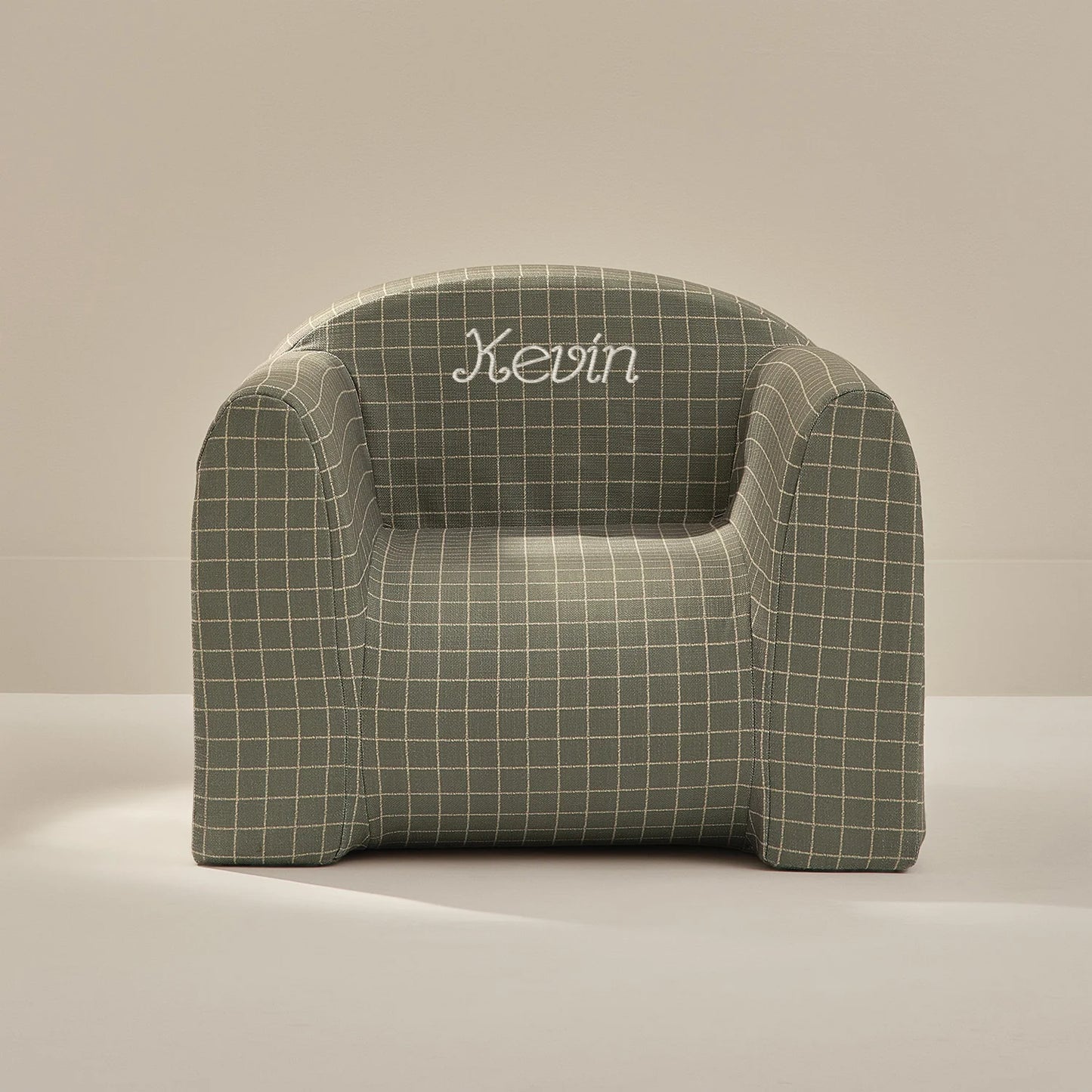 Green checkered armchair with 'Kevin' embroidered on a beige background