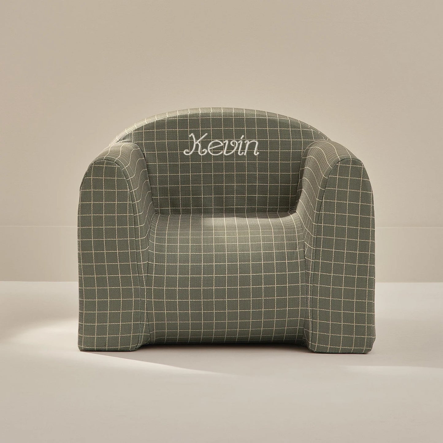 Green checkered armchair with 'Kevin' embroidered on a beige background