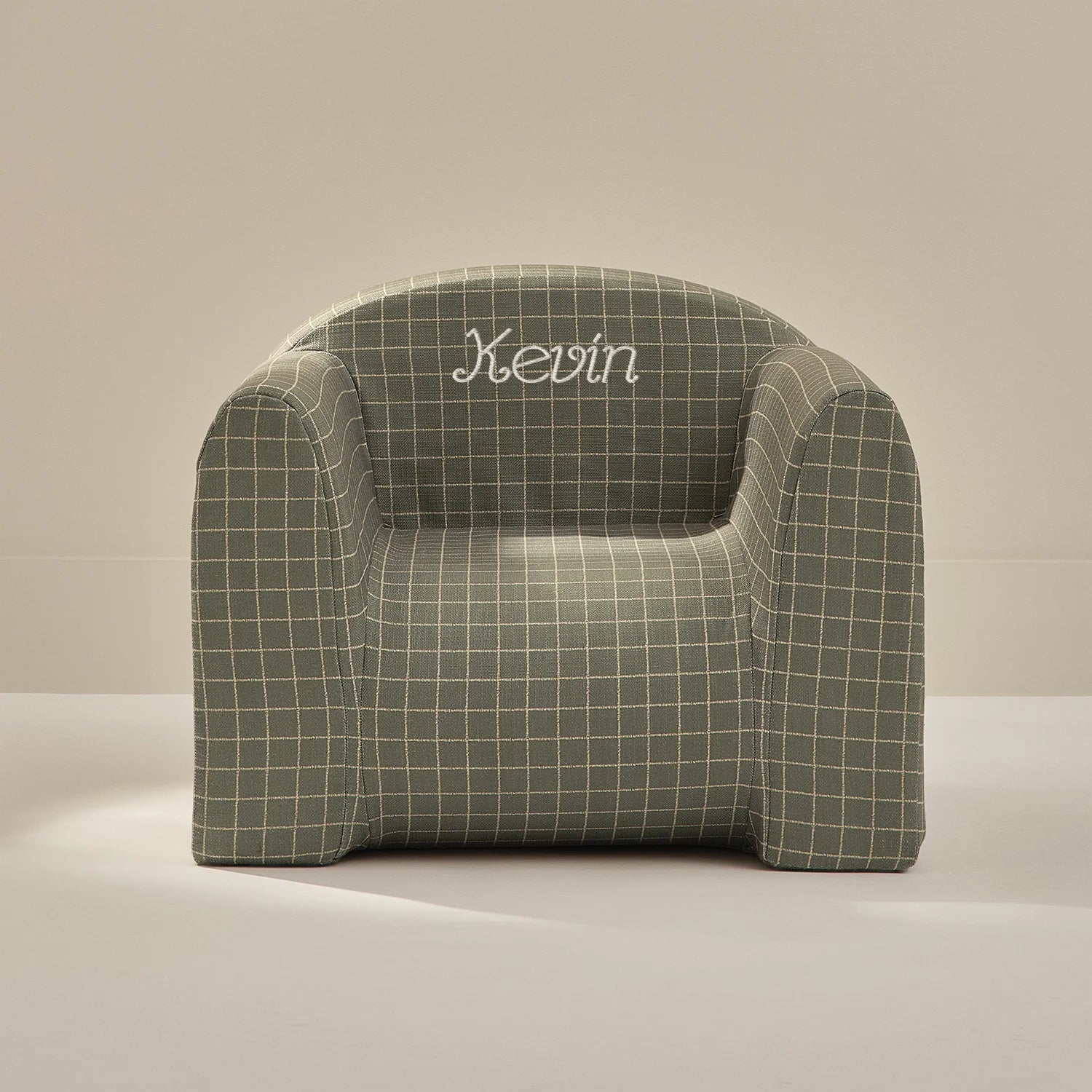 Green checkered armchair with 'Kevin' embroidered on a beige background