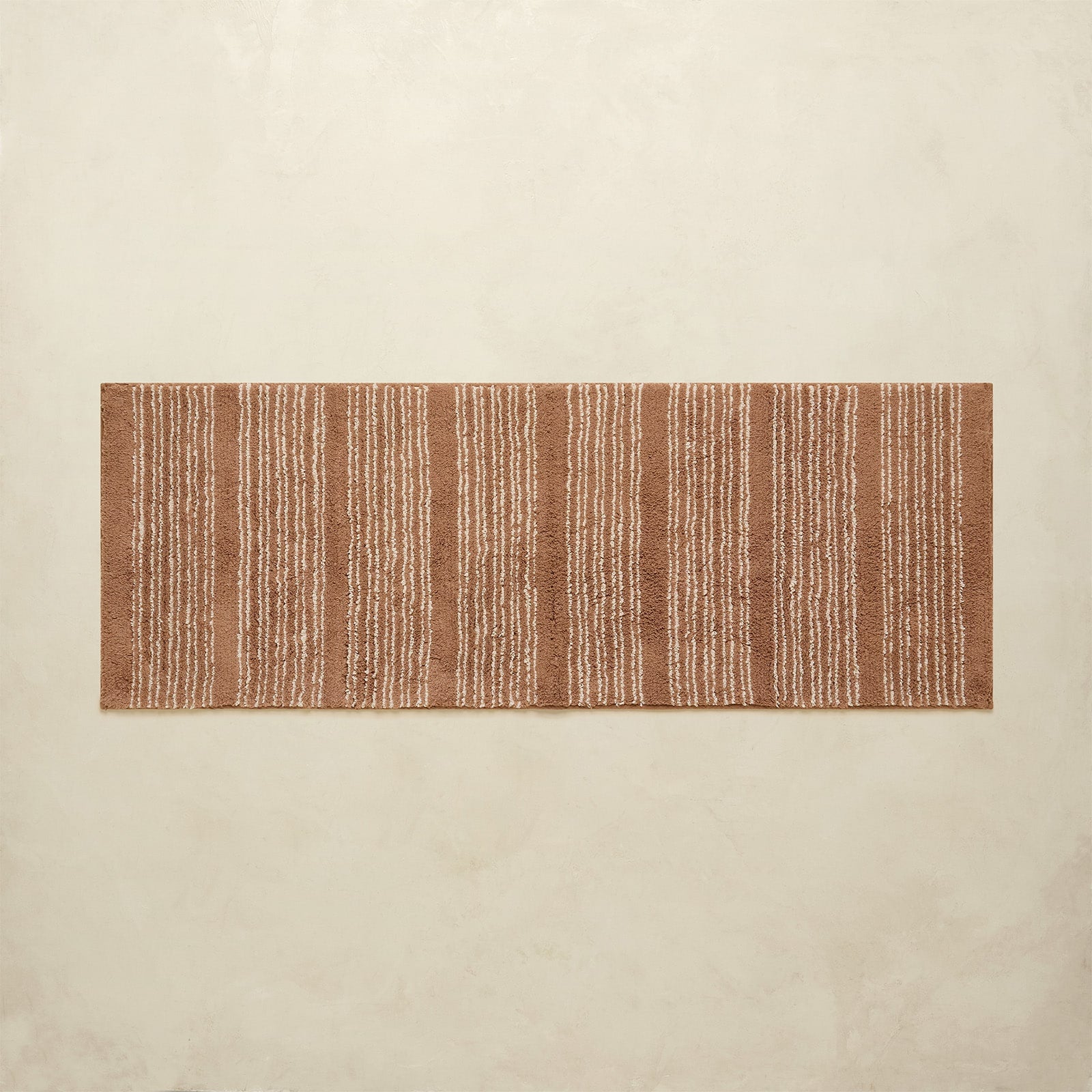 Rectangular brown and beige striped rug on a beige wall