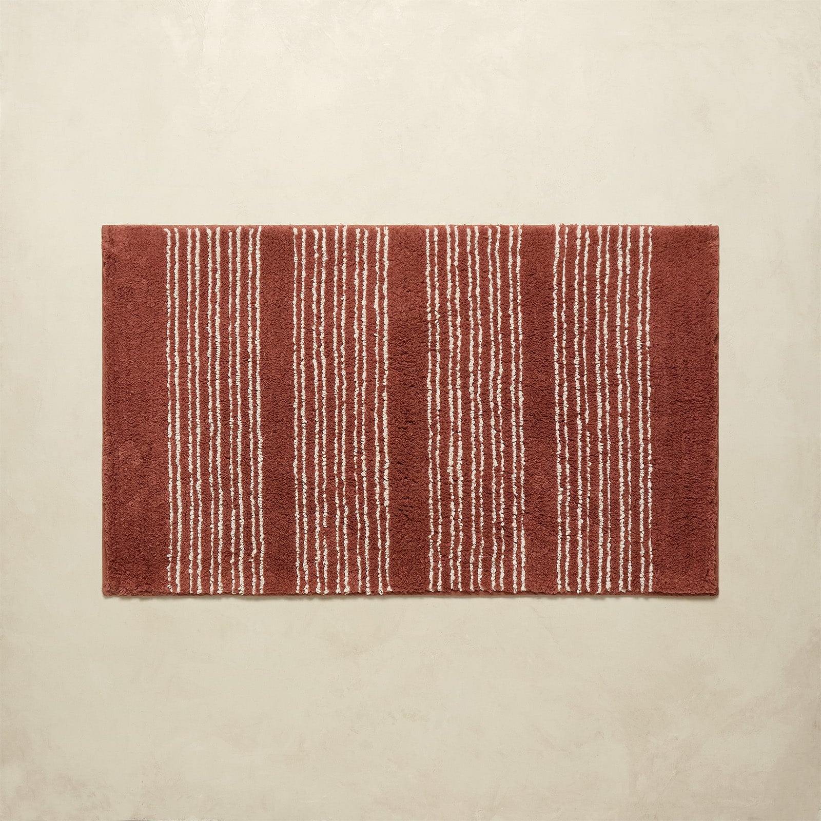 Rectangular red rug with white stripes on a beige background