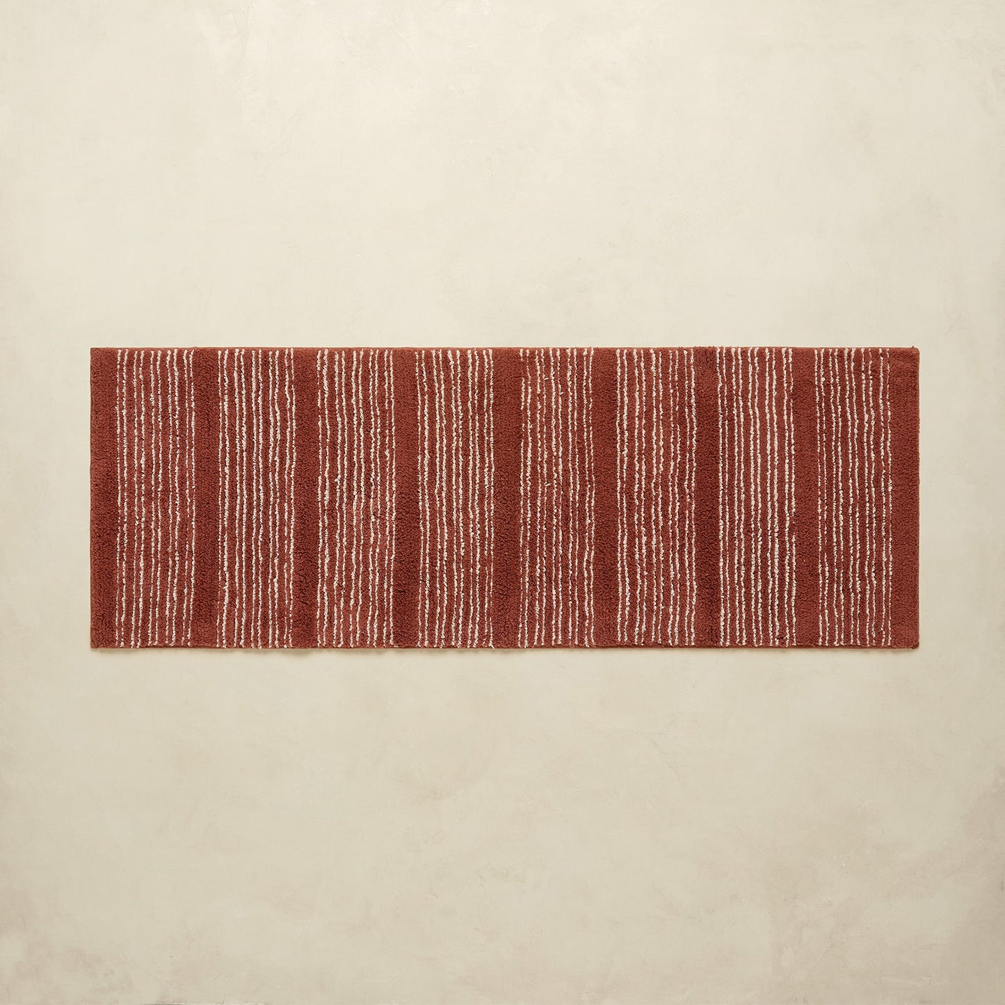 Rectangular red and white striped rug on a beige background