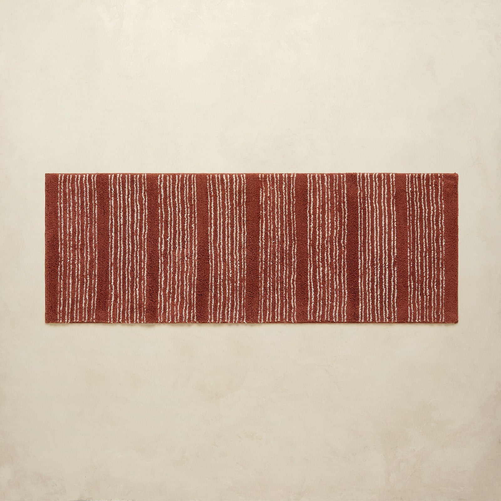 Rectangular red and white striped rug on a beige background