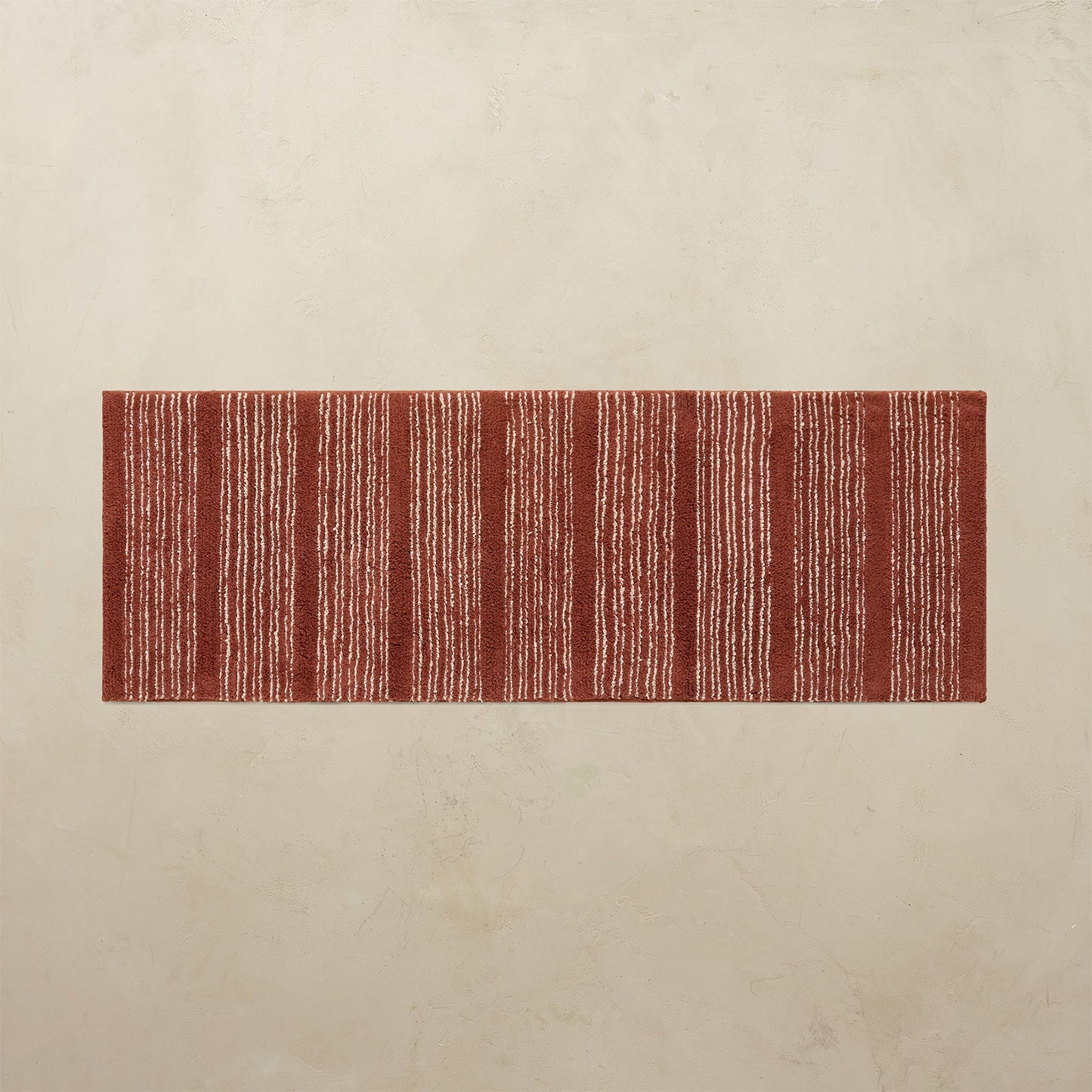 Rectangular red and white striped rug on a beige floor