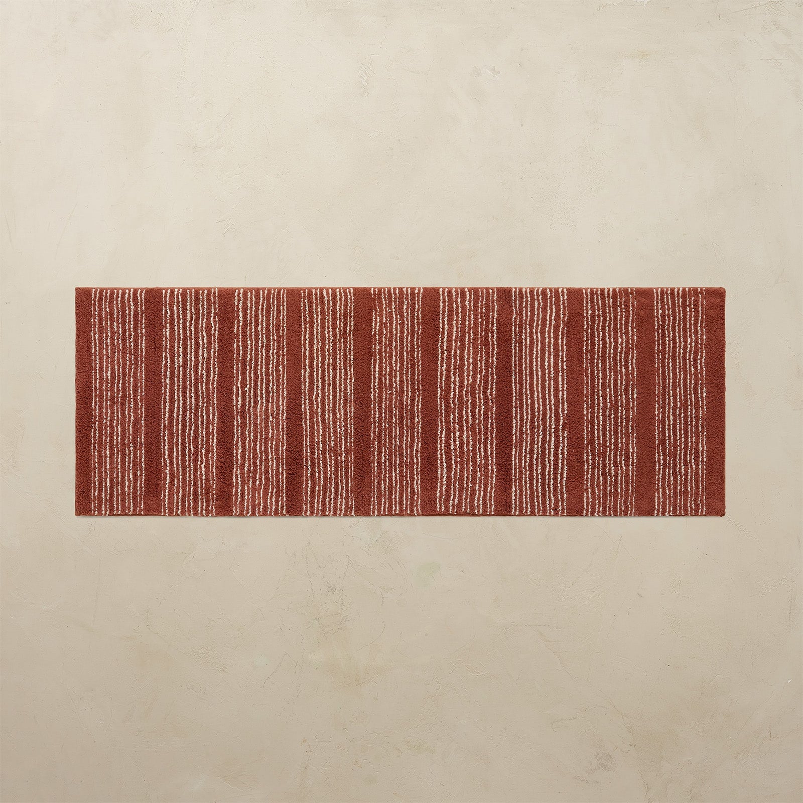 Rectangular red and white striped rug on a beige floor